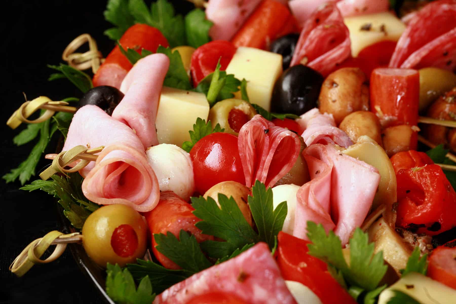 A charcuterie wreath, made up of antipasto skewers featuring various meats, cheeses, and olives.