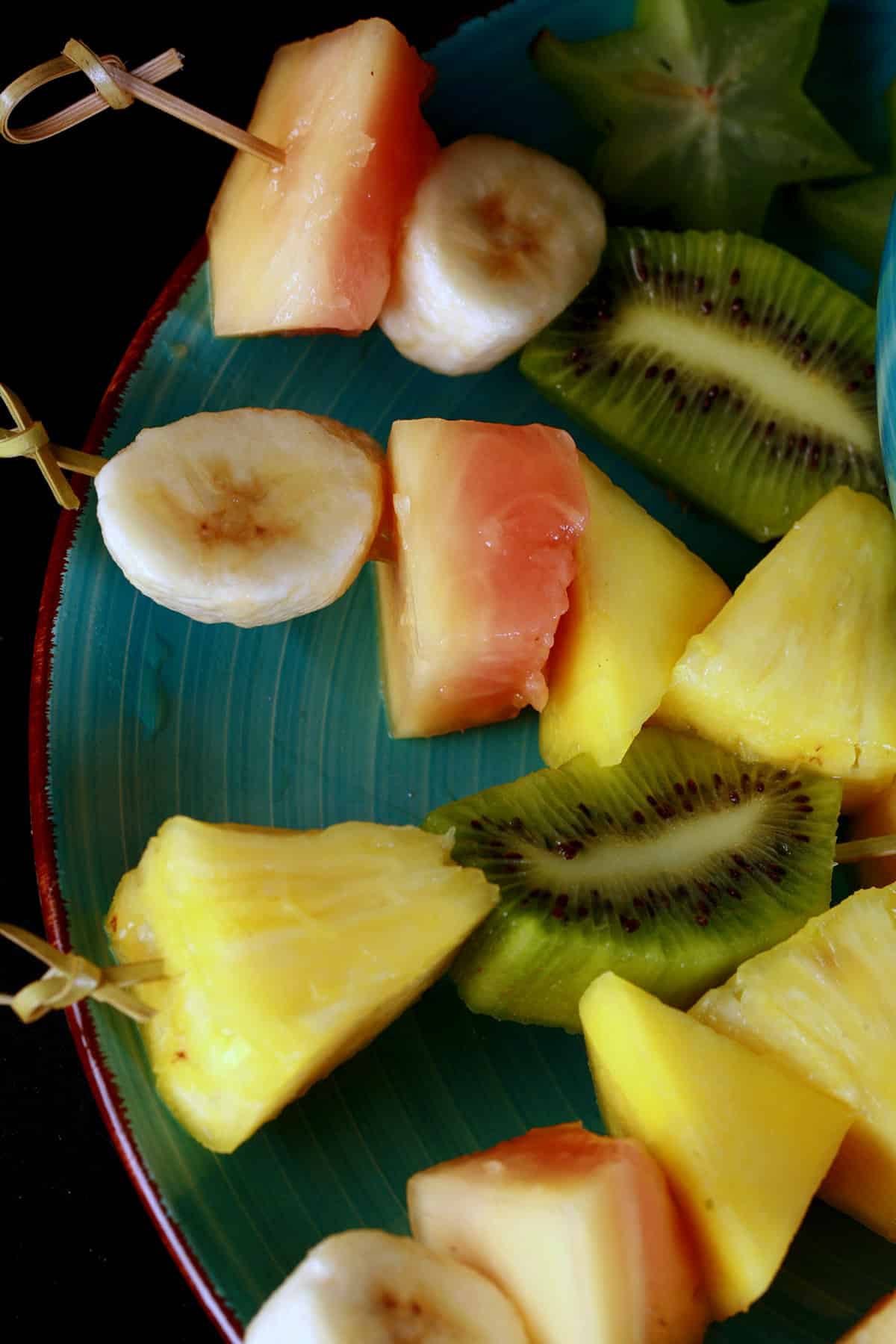 A plate of mixed fruit tropical skewers.