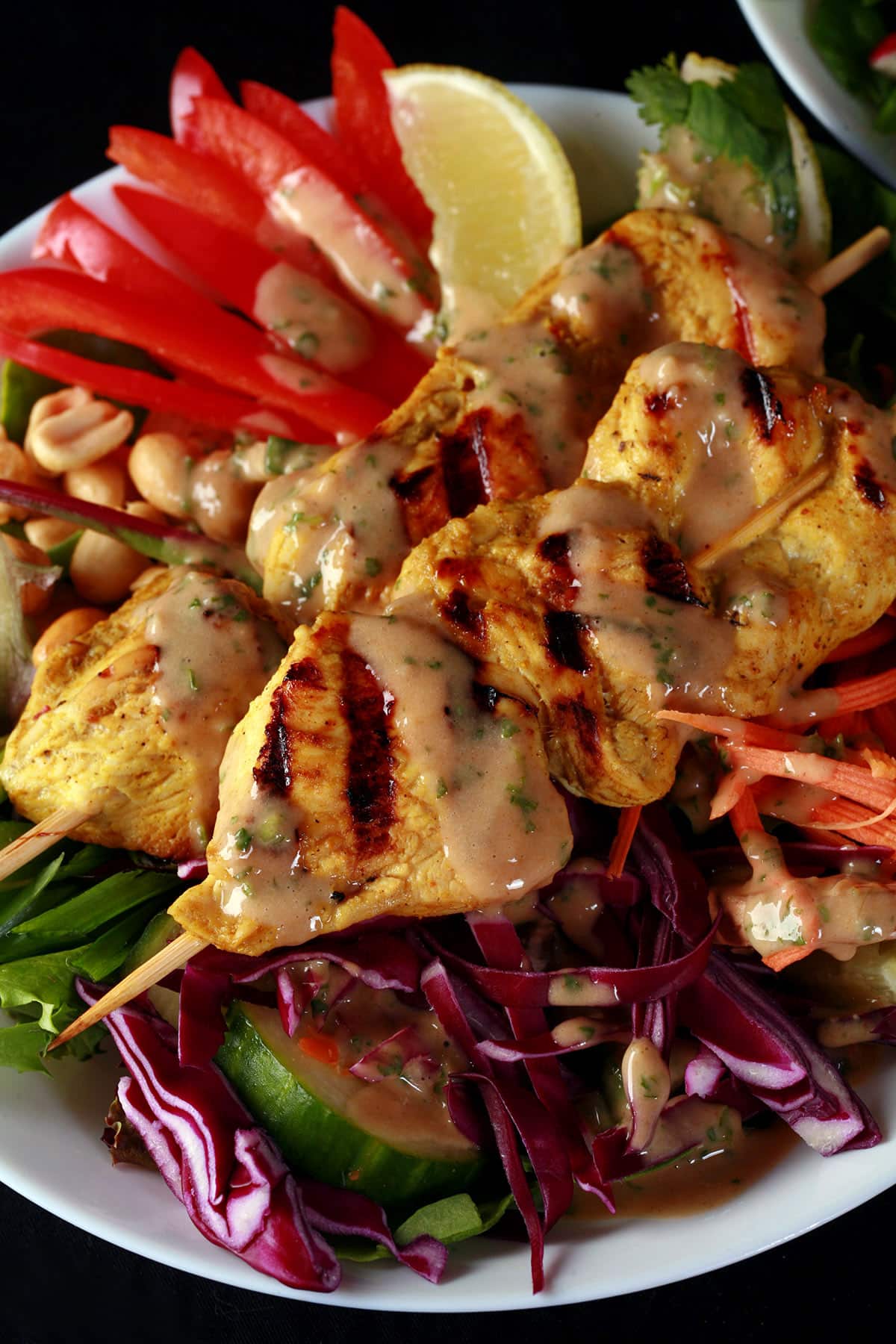 A grilled chicken satay salad drizzled with peanut dressing.
