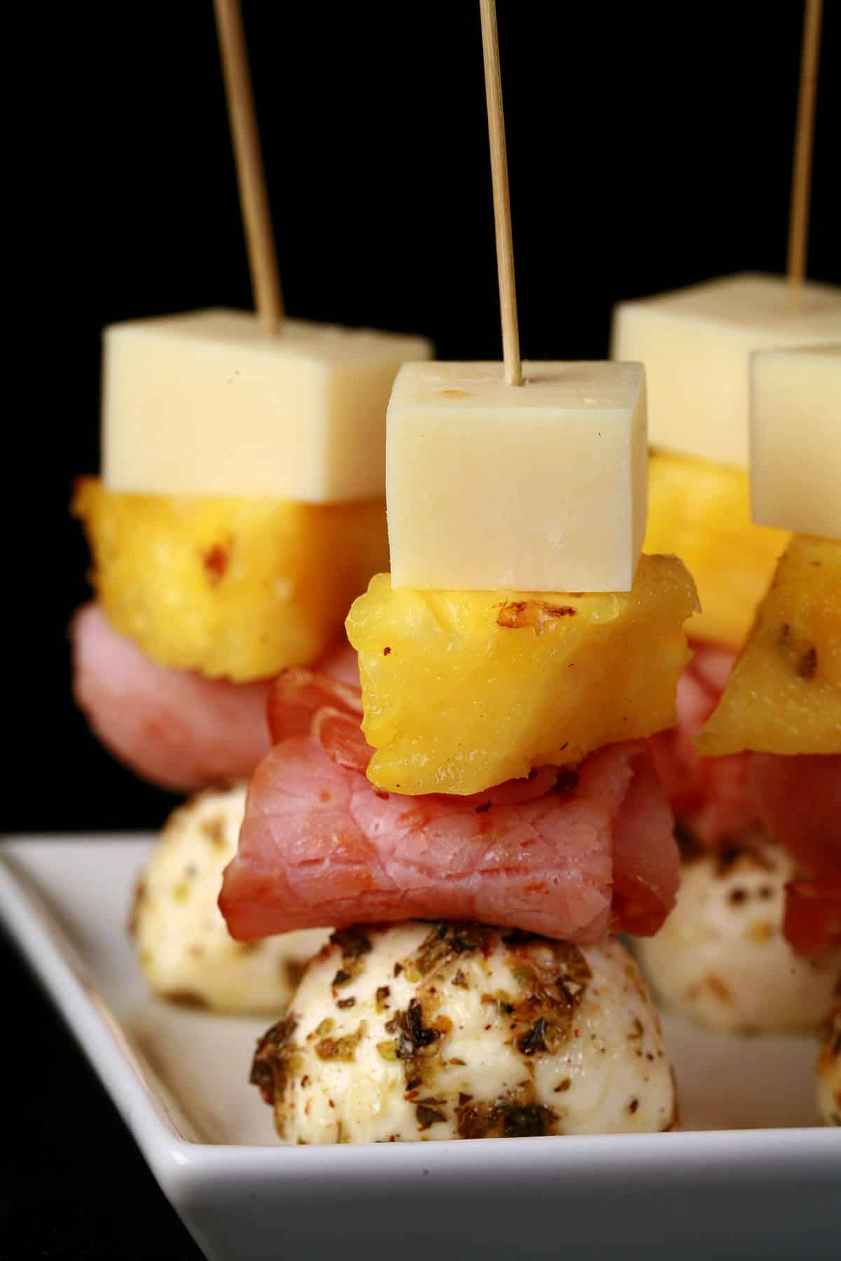 A tray of hawaiian pizza skewers - pineapple, back bacon, and 2 kinds of cheese.