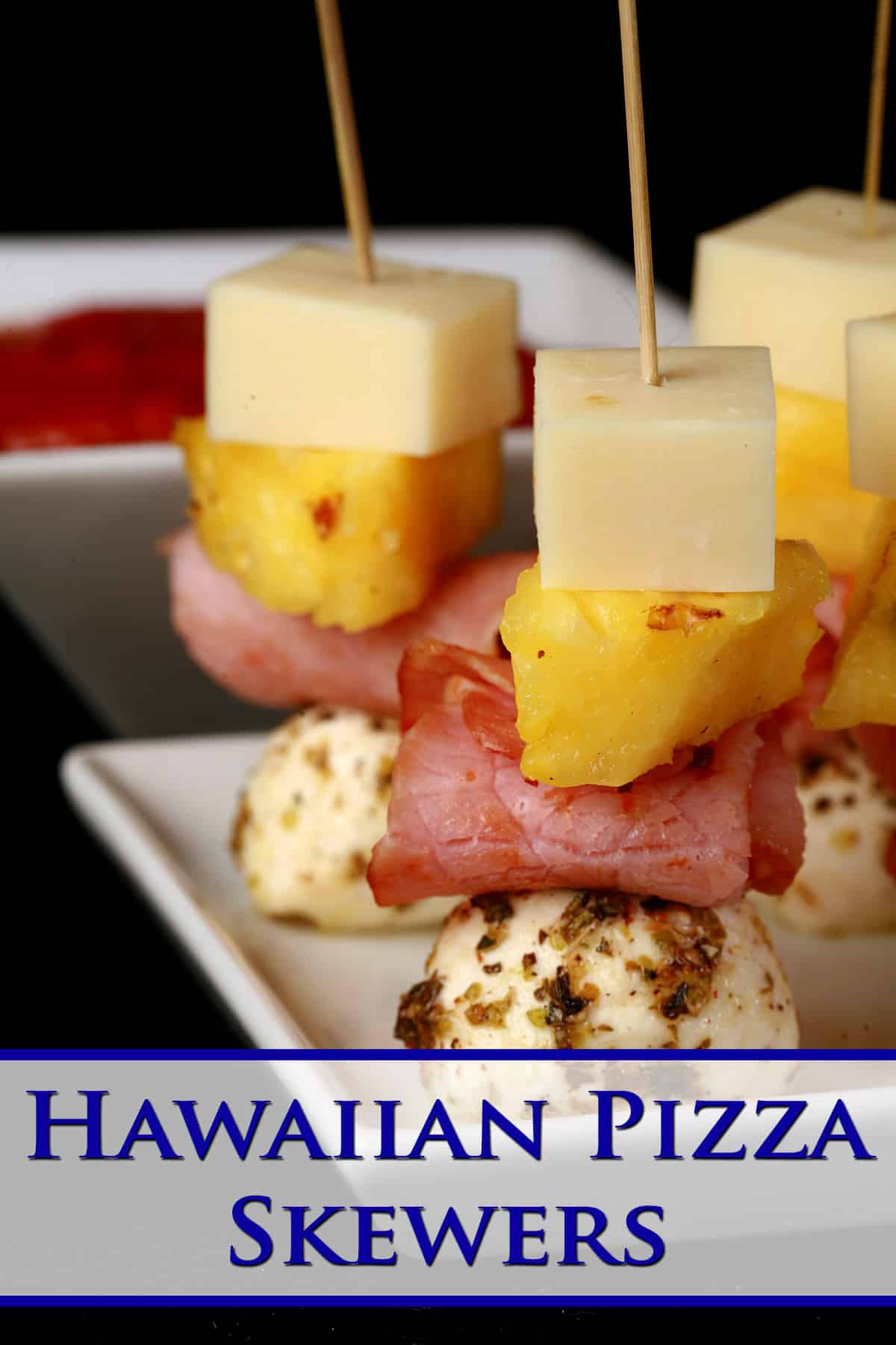 A tray of hawaiian pizza themed ham and pineapple skewers.
