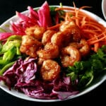 A colourful salad topped with honey ginger shrimp.