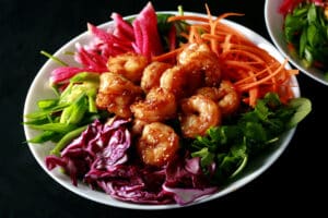 A colourful salad topped with honey ginger shrimp.