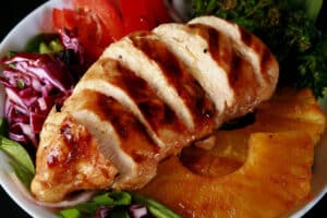 A grilled teriyaki chicken salad with fresh pineapple slices.