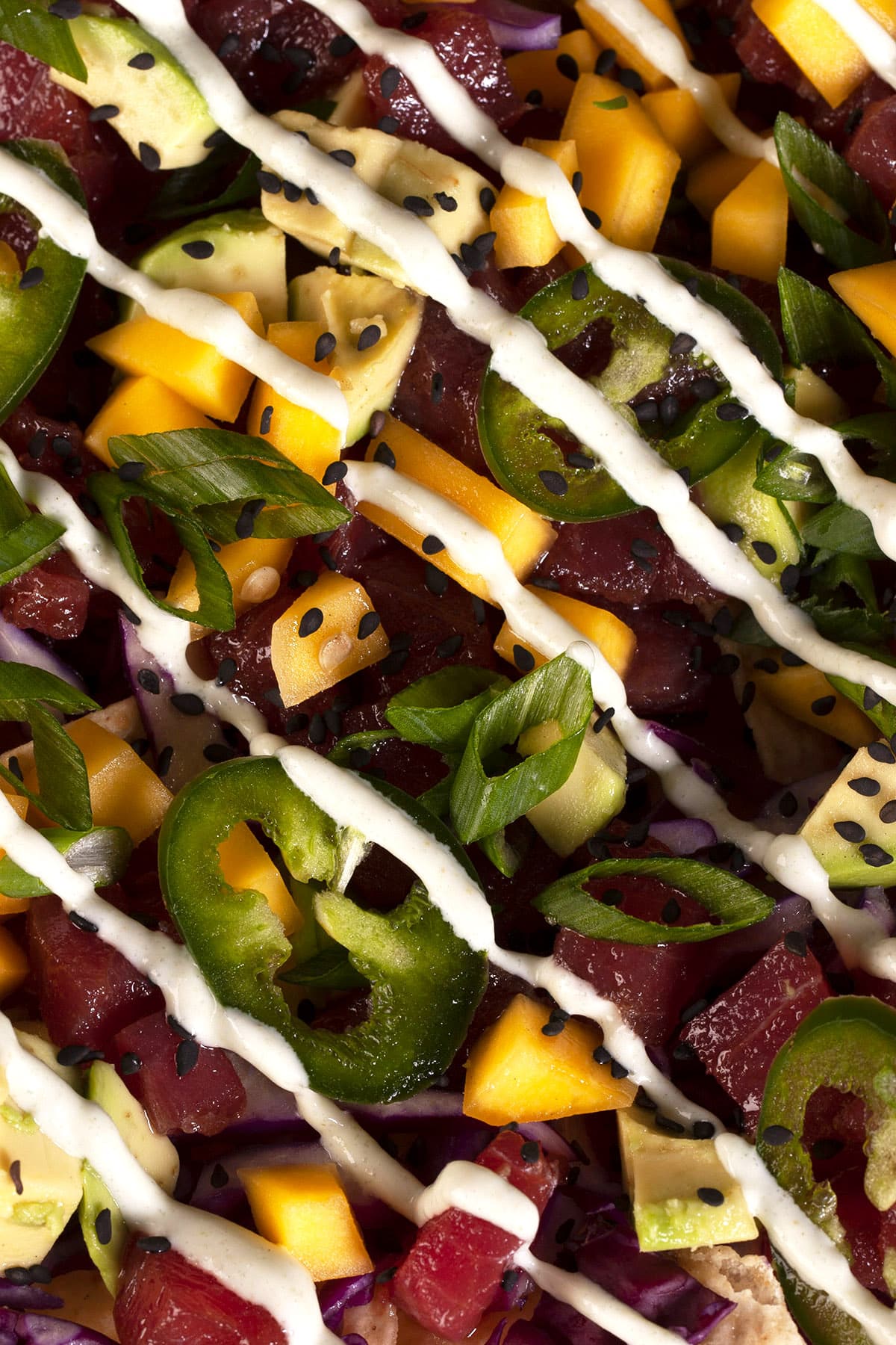 A close up photo of a platter of ahi tuna nachos drizzled with wasabi mayo.