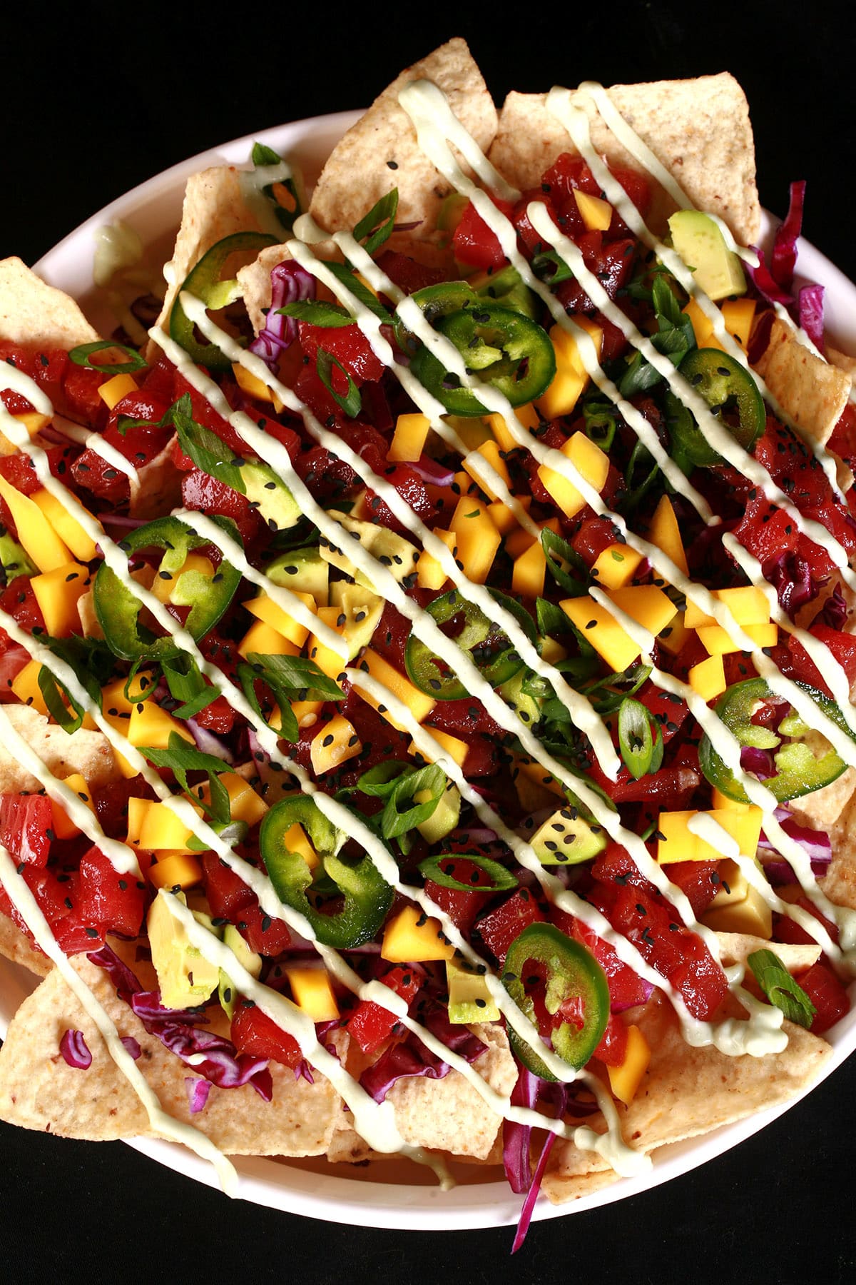 A platter of tuna poke nachos, with mango, avocado, purple cabbage, jalapeno slices, and wasabi mayo.