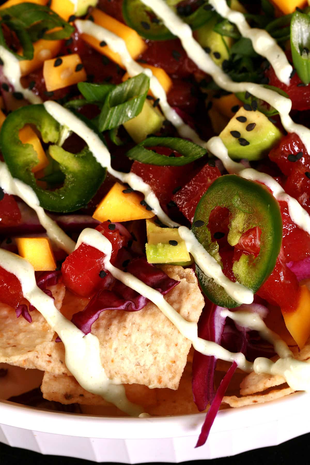 A close up photo of a platter of ahi tuna nachos drizzled with wasabi mayo.