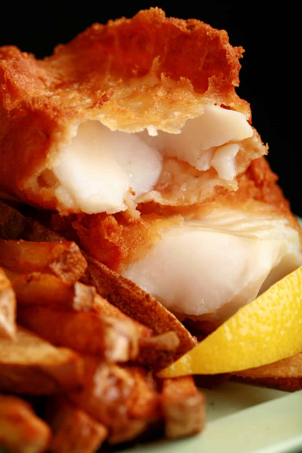 A plate of gluten free fish and chips, with a wedge of lemon.