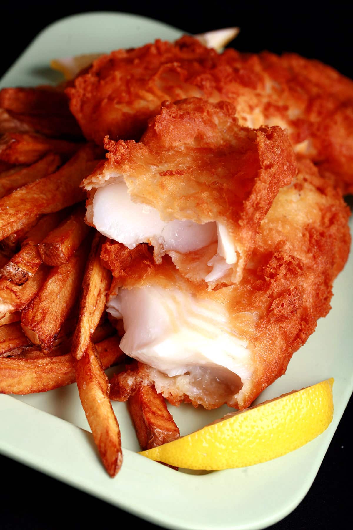 A plate of gluten free fish and chips, with a wedge of lemon.