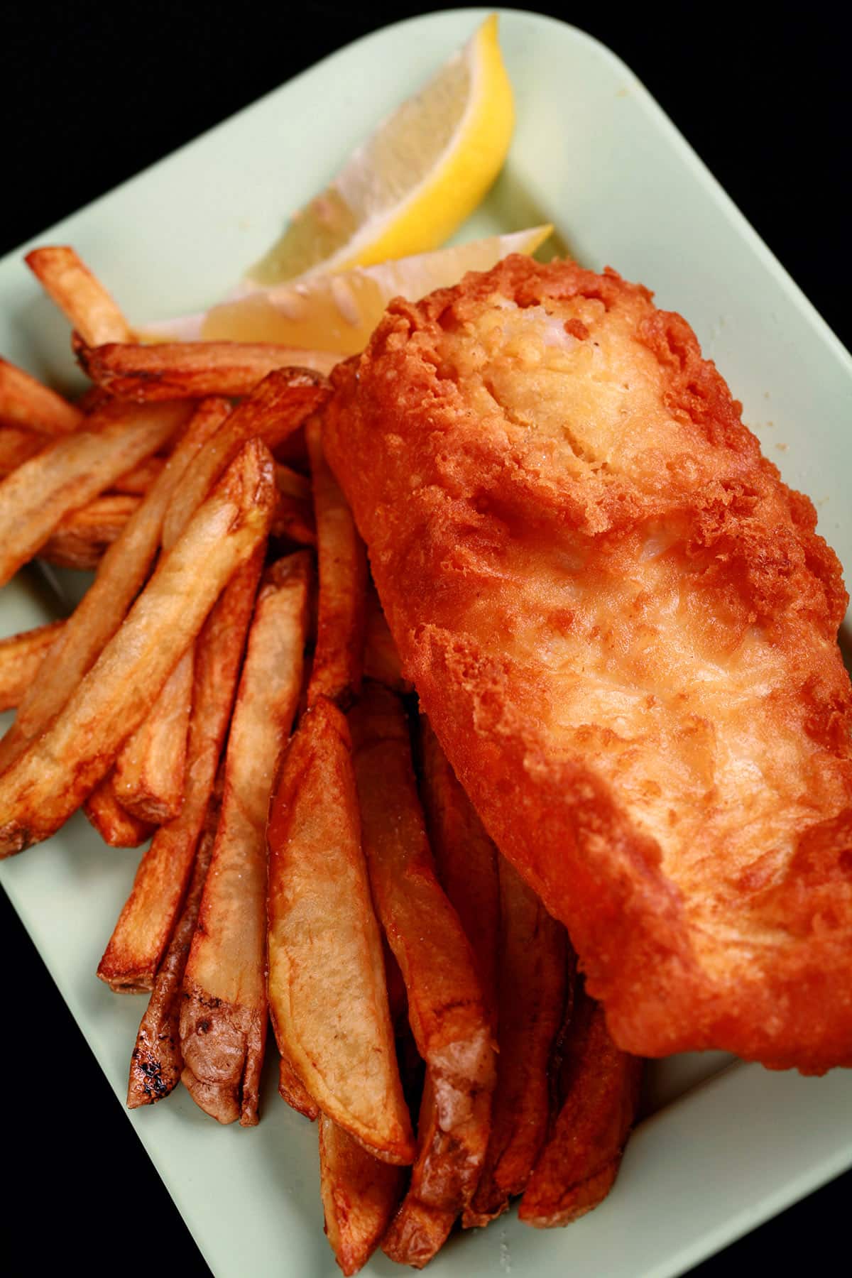 A plate of gluten-free fish and chips, with a wedge of lemon.