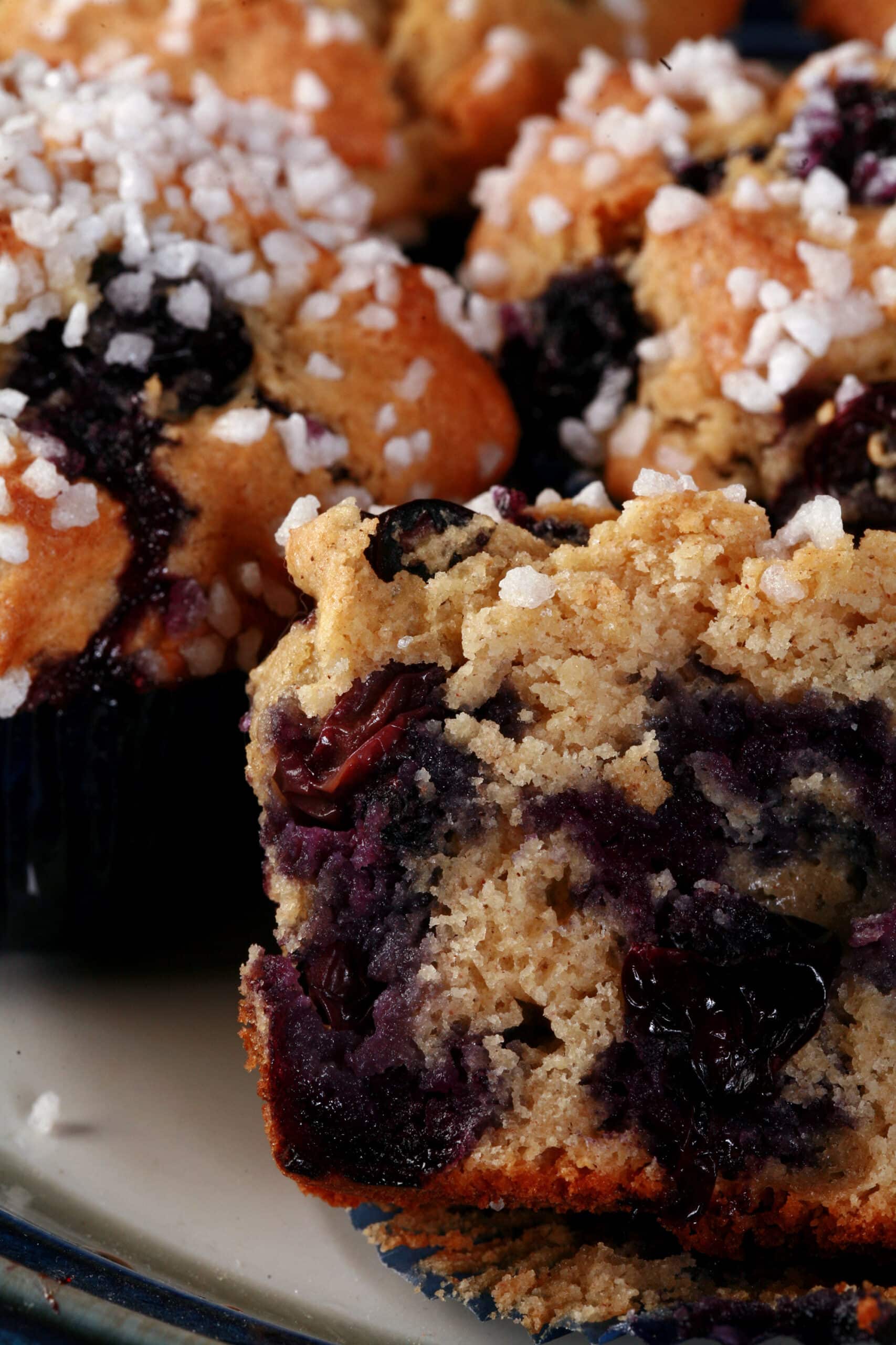 Several sugar topped gluten-free blueberry muffins on a plate.