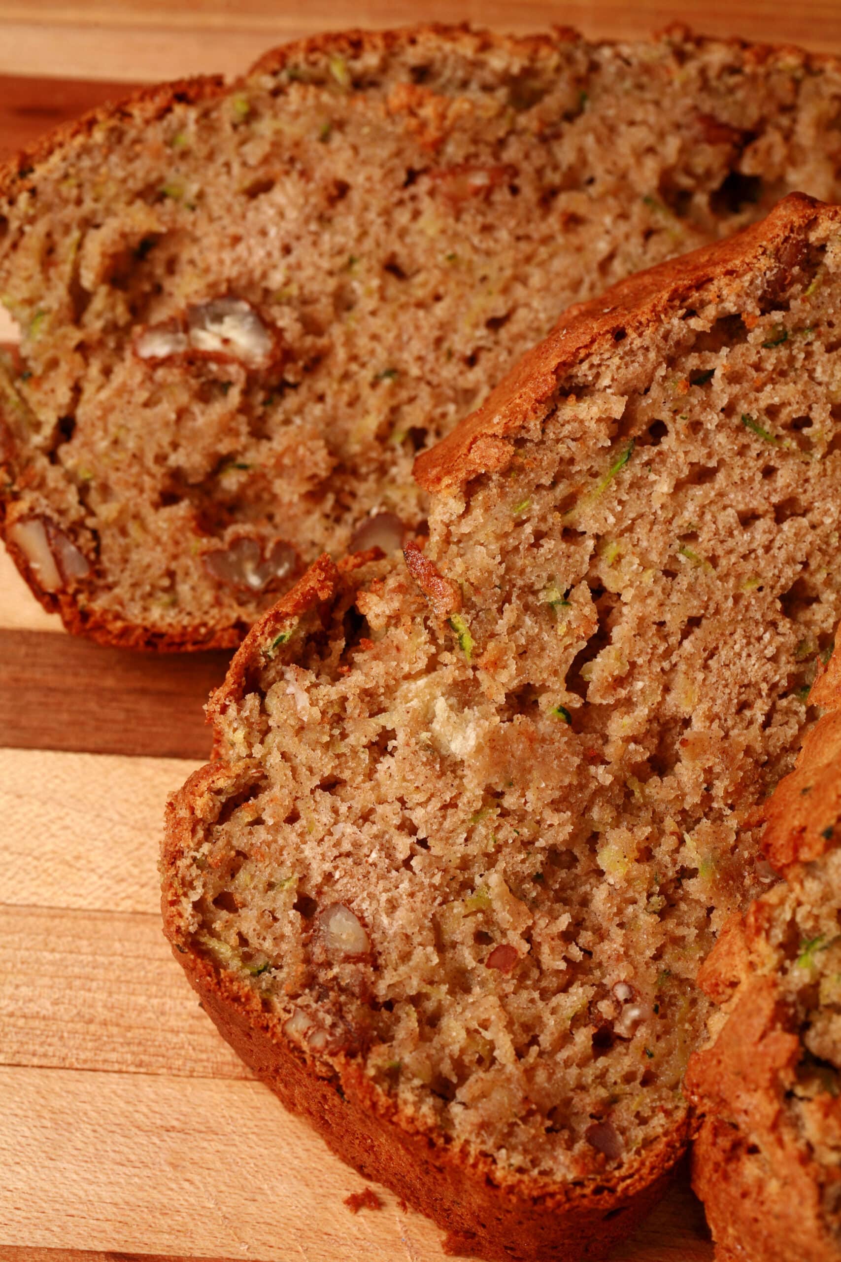 A sliced loaf of gluten-free zucchini bread on a wooden cutting board.