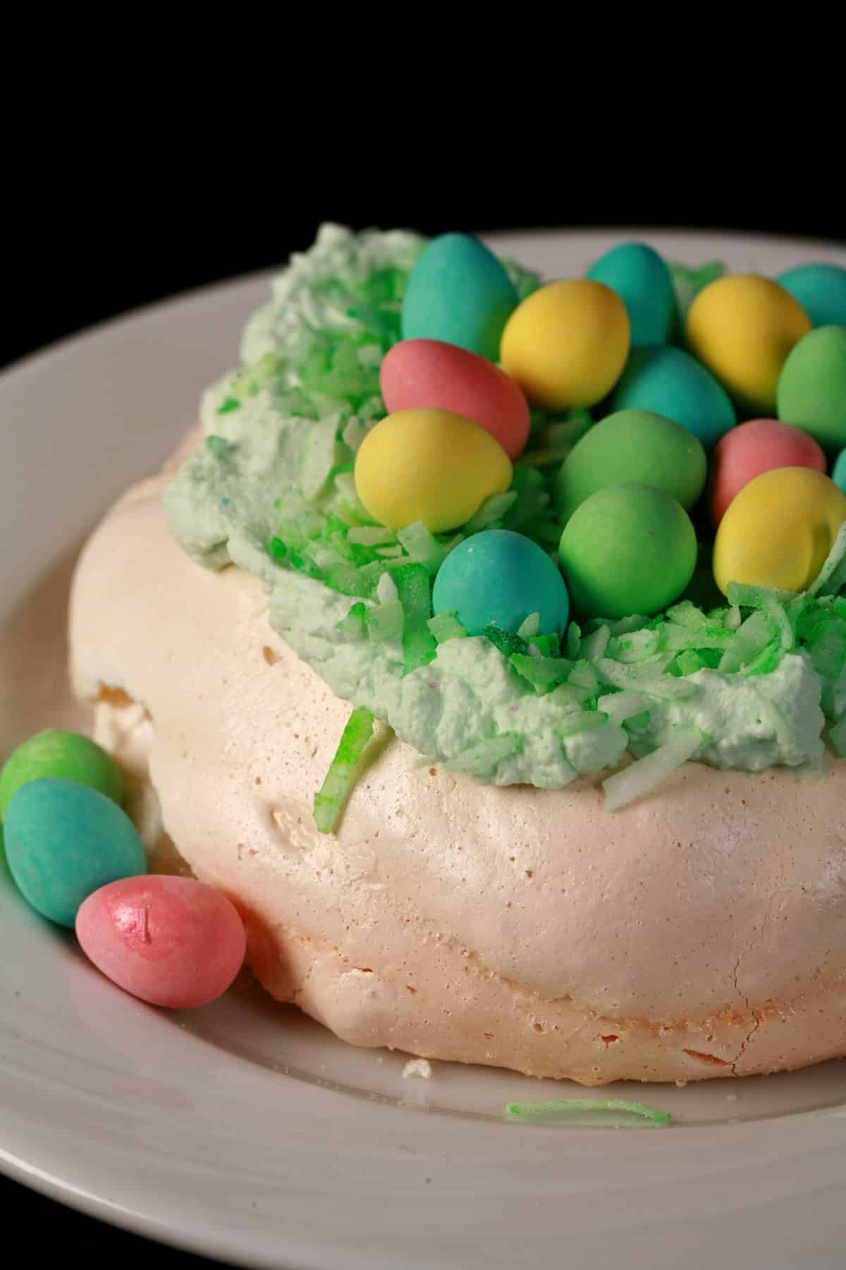 A single mini Easter pavlova, topped with green coconut and cadbury mini eggs.
