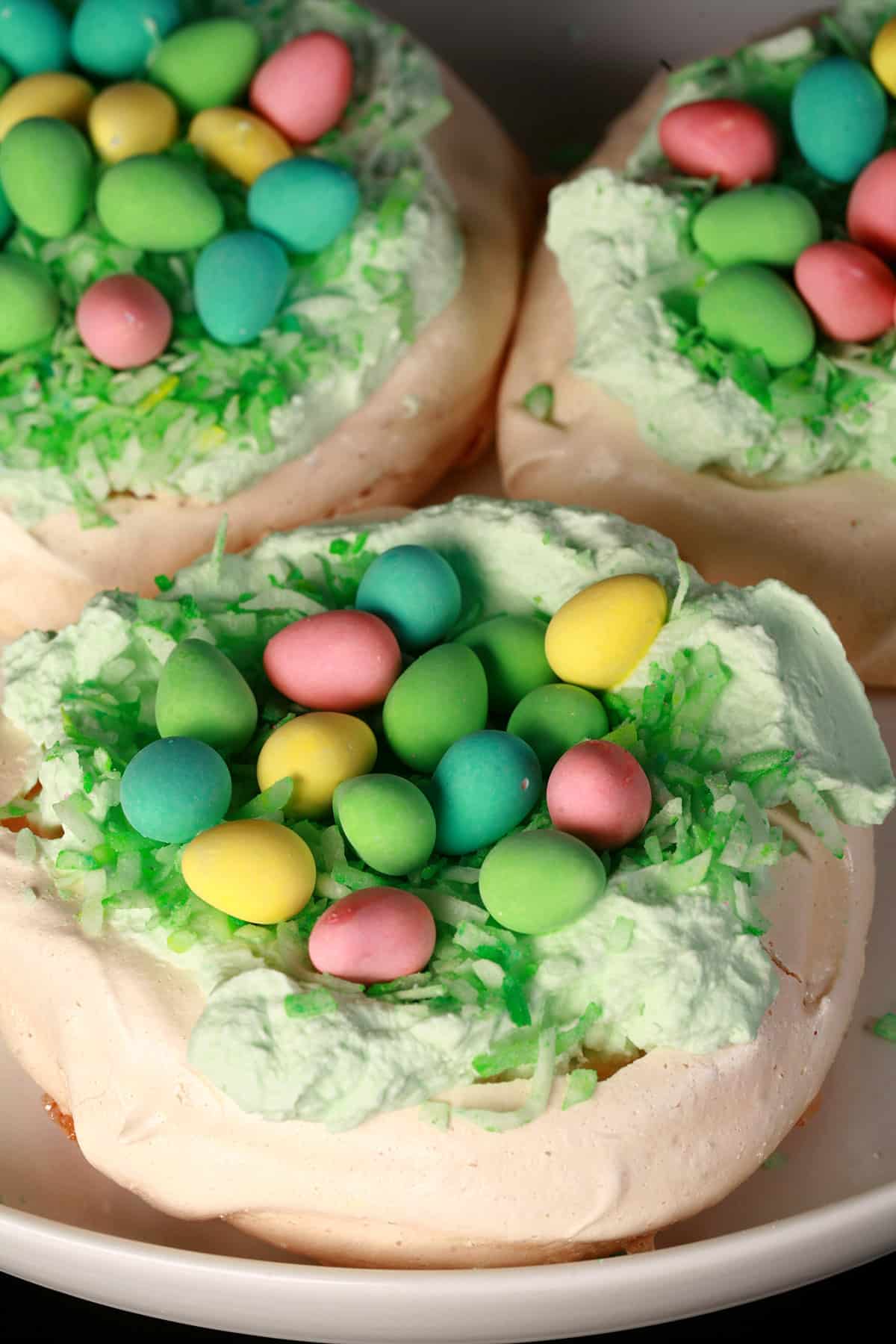 A trio of Easter themed mini pavlovas. Each is topped with mini chocolate eggs