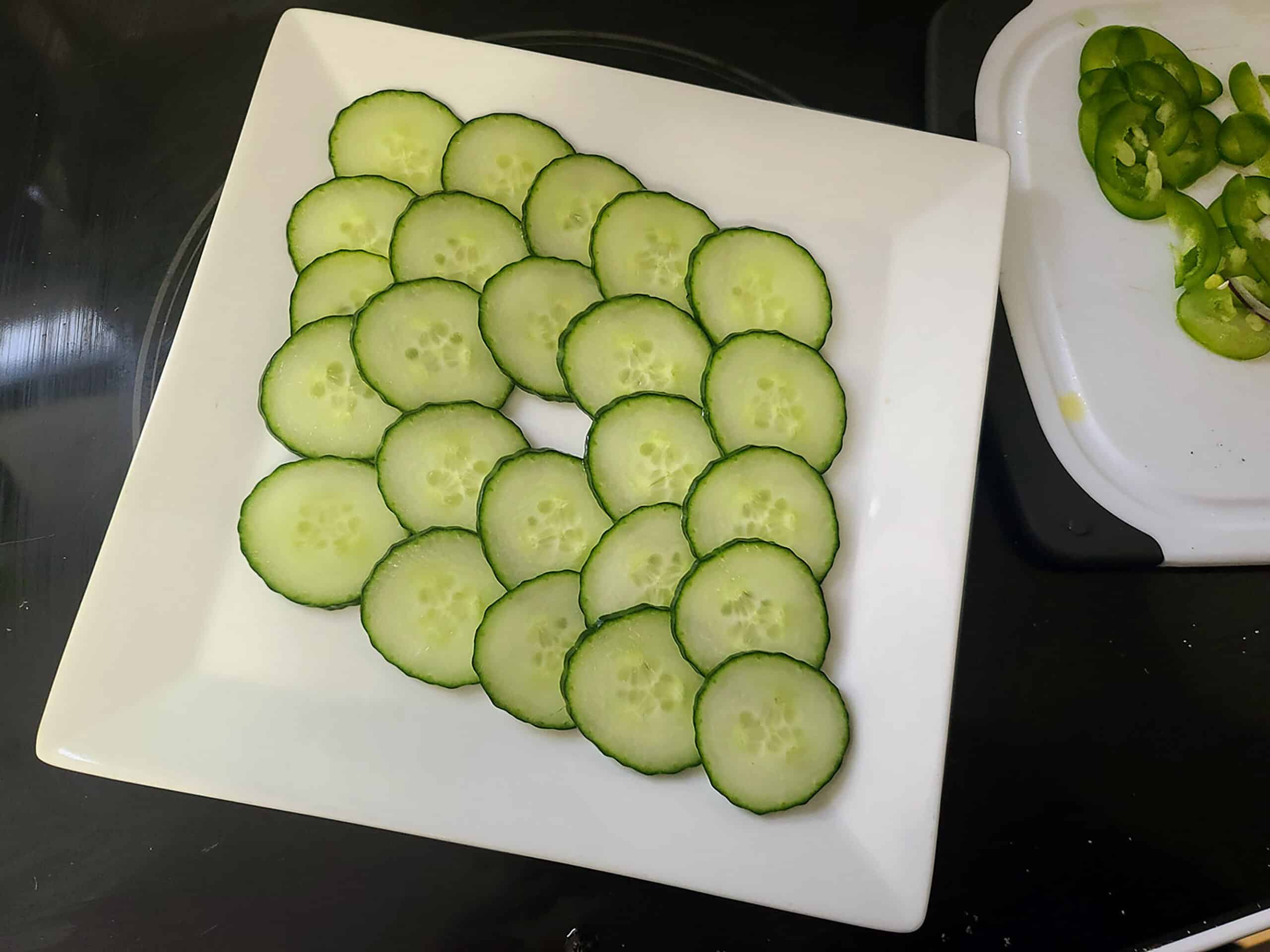 Thin cucumber slices are arranged in a diamond pattern on a white plate.