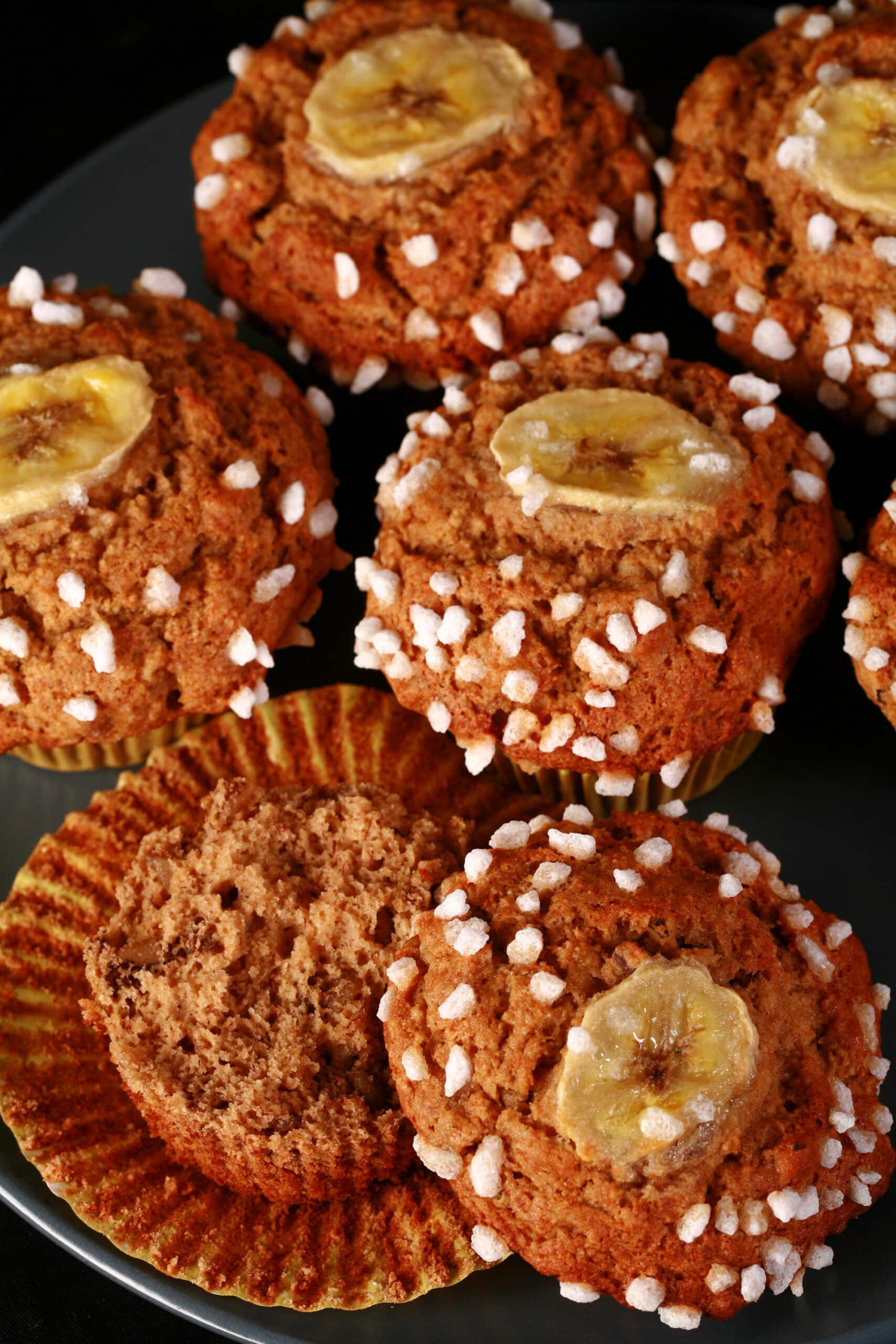 A plate of gluten-free banana muffins, topped with coarse sugar and banana slices.