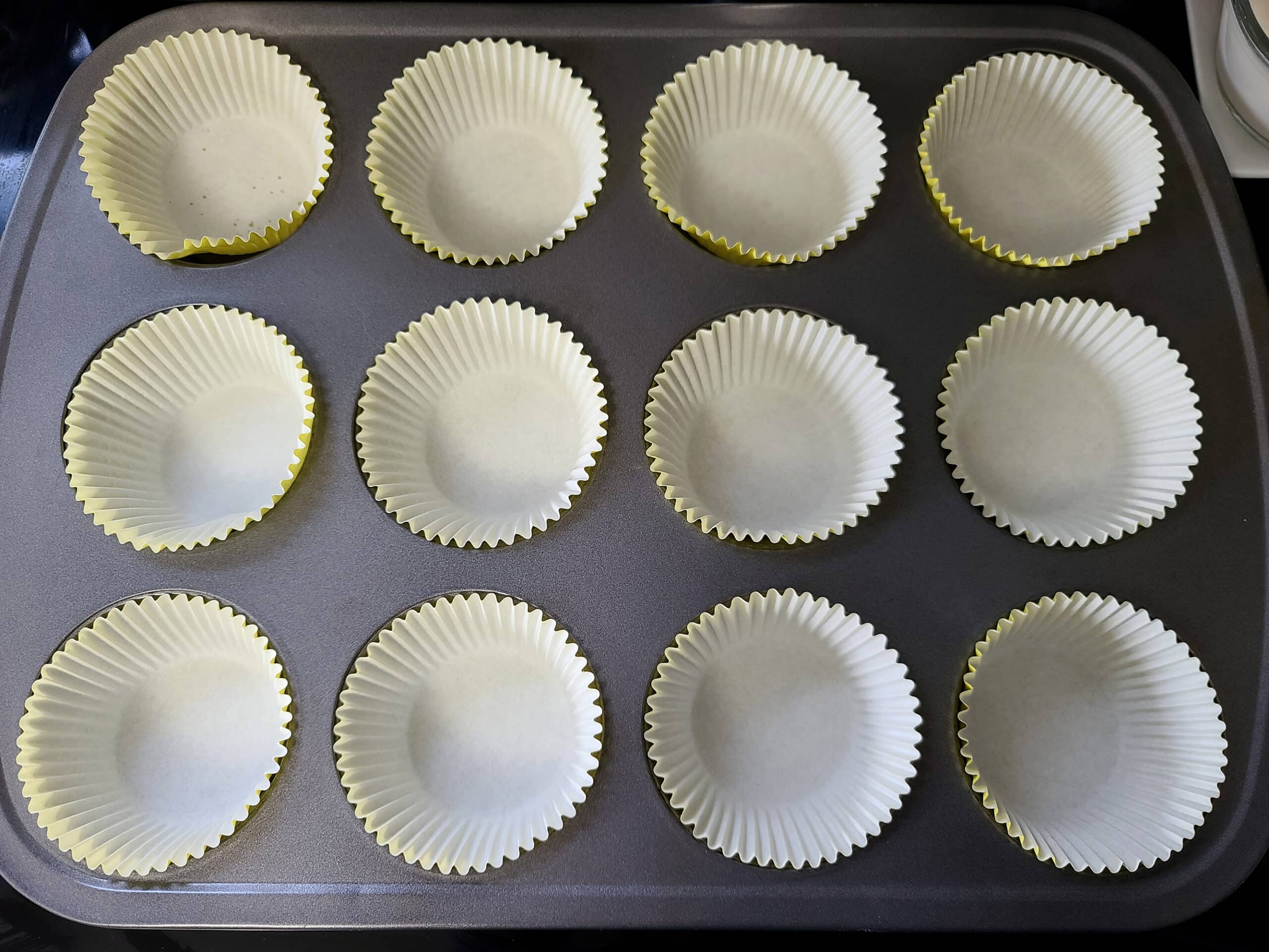 A muffin pan lined with white cupcake liners.
