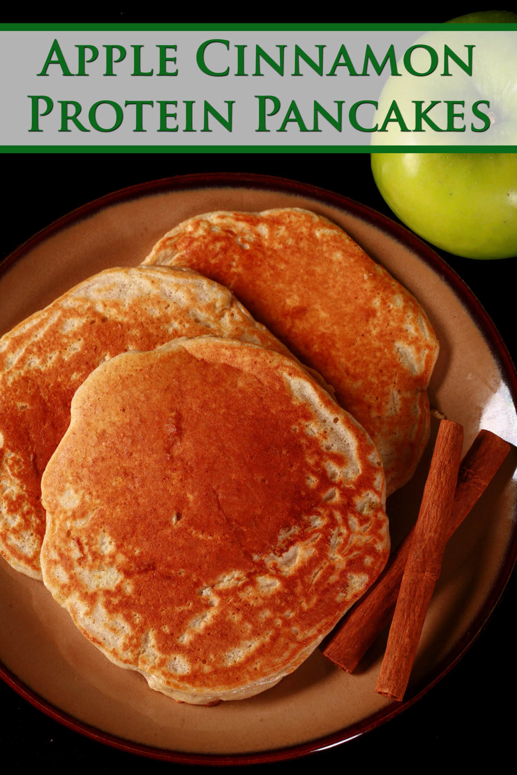 3 apple cinnamon protein pancakes on a plate, with 2 cinnamon sticks.  Green text says apple cinnamon protein pancakes.