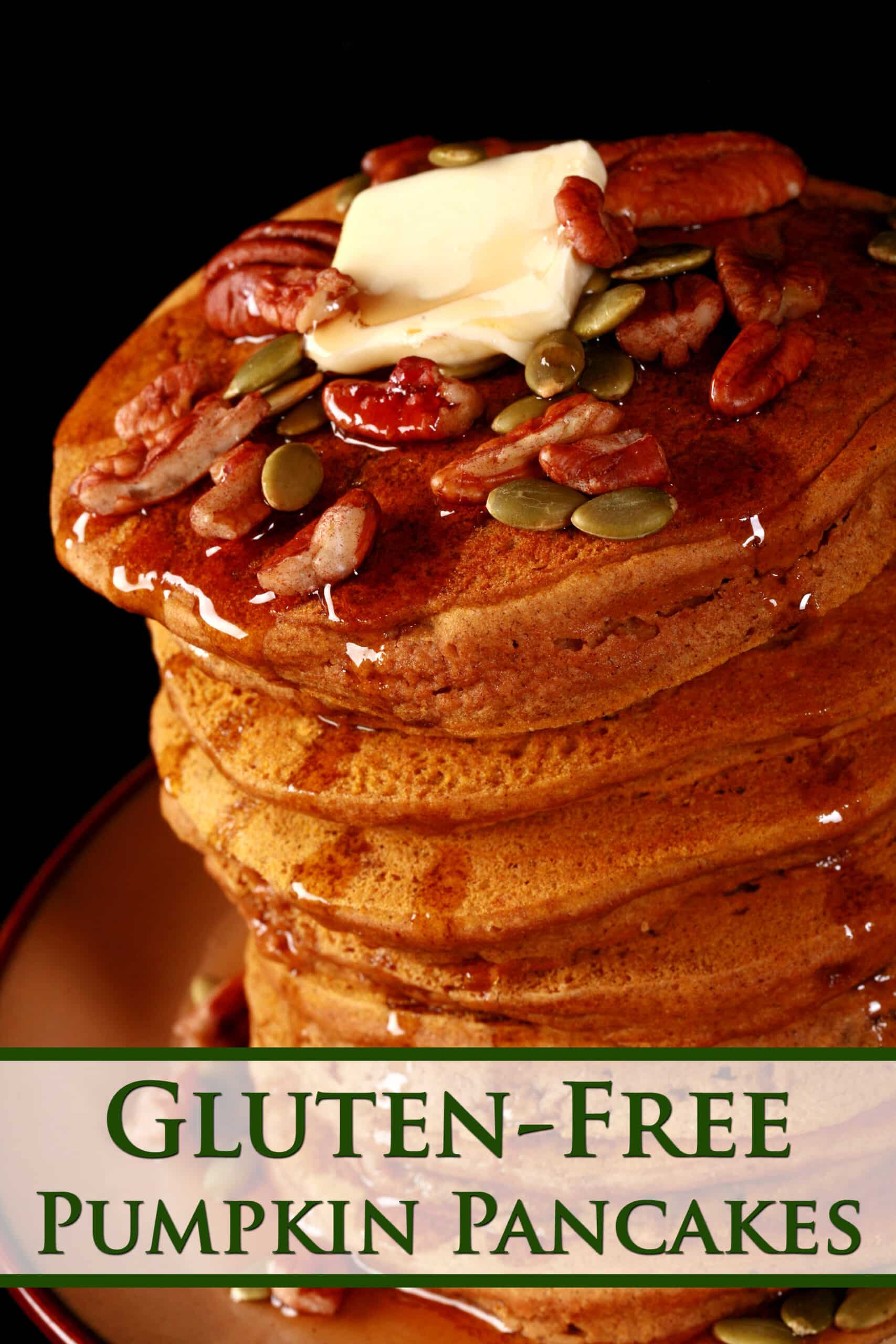 A tall stack of pumpkin pancakes, topped with butter, maple syrup, pecans, and pumpkin seeds. Overlaid text says gluten free pumpkin pancakes.