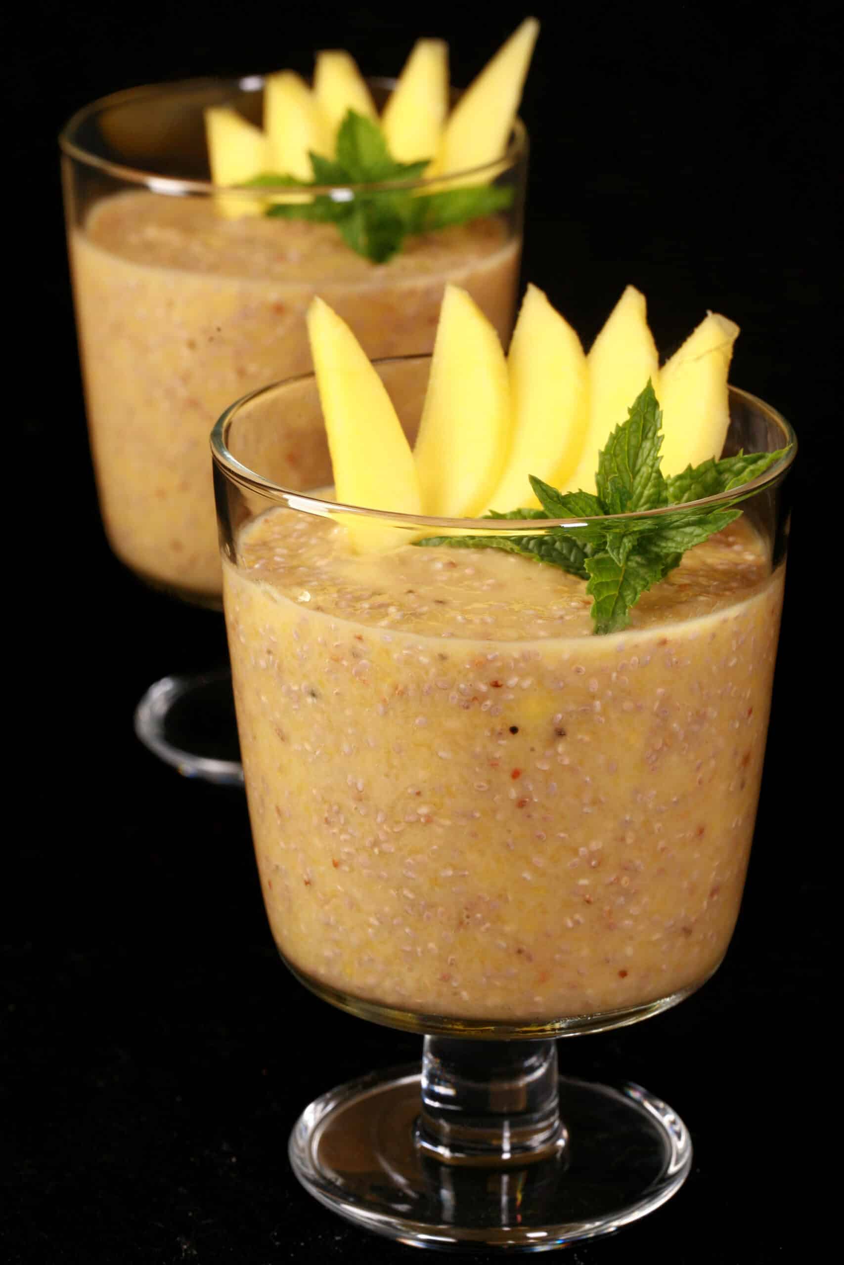 2 glasses of mango chia pudding, garnished with mango slices and fresh mint leaves.