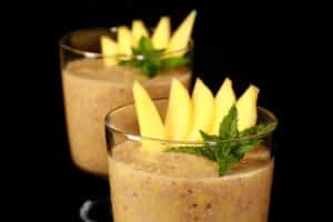 2 glasses of mango chia seed pudding, garnished with mango slices and fresh mint leaves.