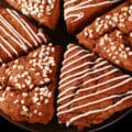 A plate of gluten-free gingerbread scones. Half have a sugar crust, the other half have a vanilla glaze drizzled over them.