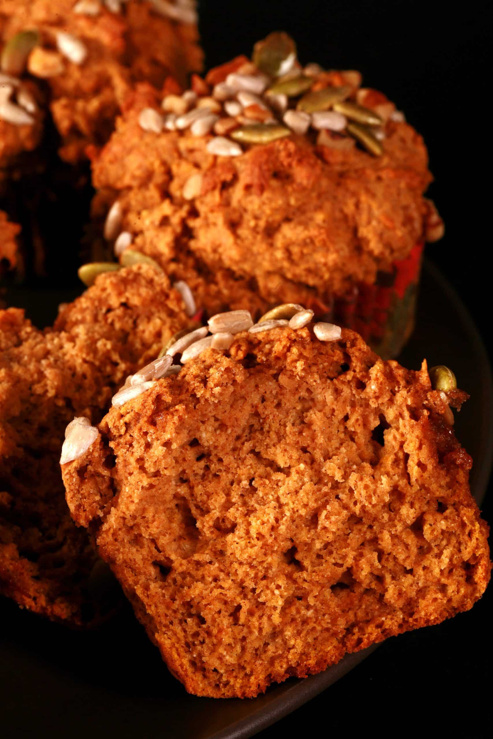 A plate of gluten free pumpkin muffins, all topped with a mix of seeds and nuts.