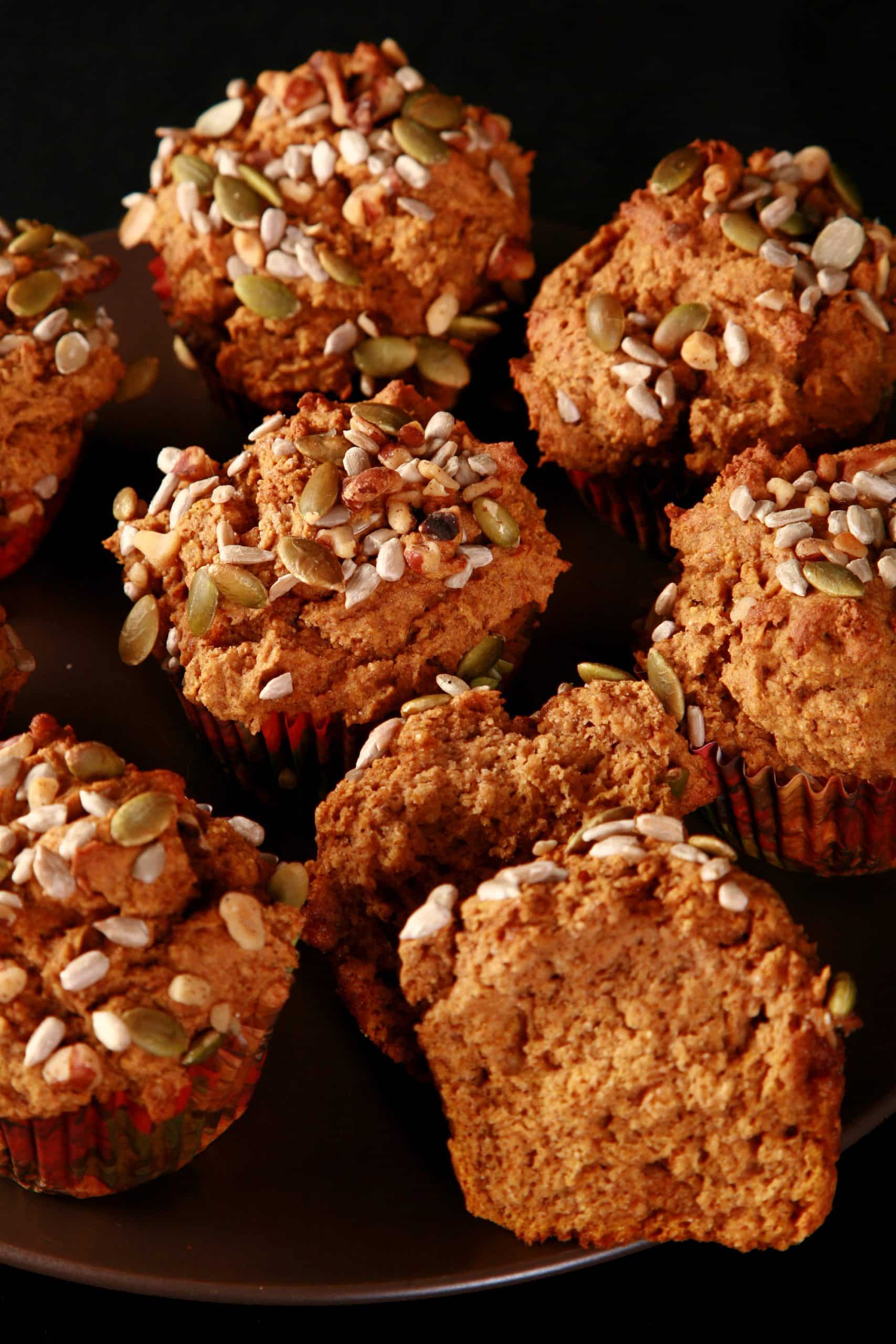 A plate of gluten free pumpkin muffins, all topped with a mix of seeds and nuts.