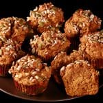 A plate of gluten-free pumpkin muffins, all topped with a mix of seeds and nuts.