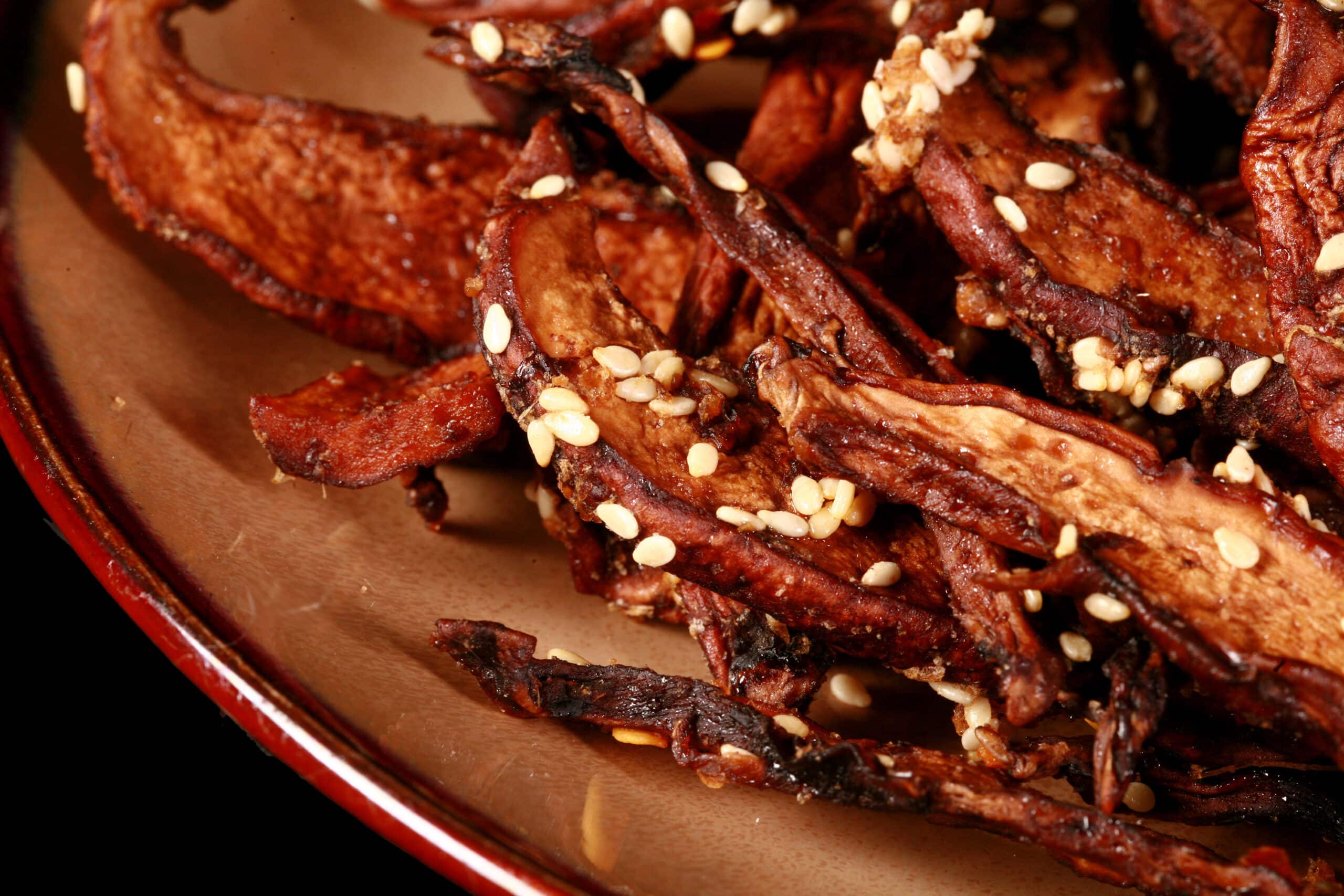 A plate of homemade mushroom jerky made from portabello mushroom slices. This batch has sesame seeds visible.