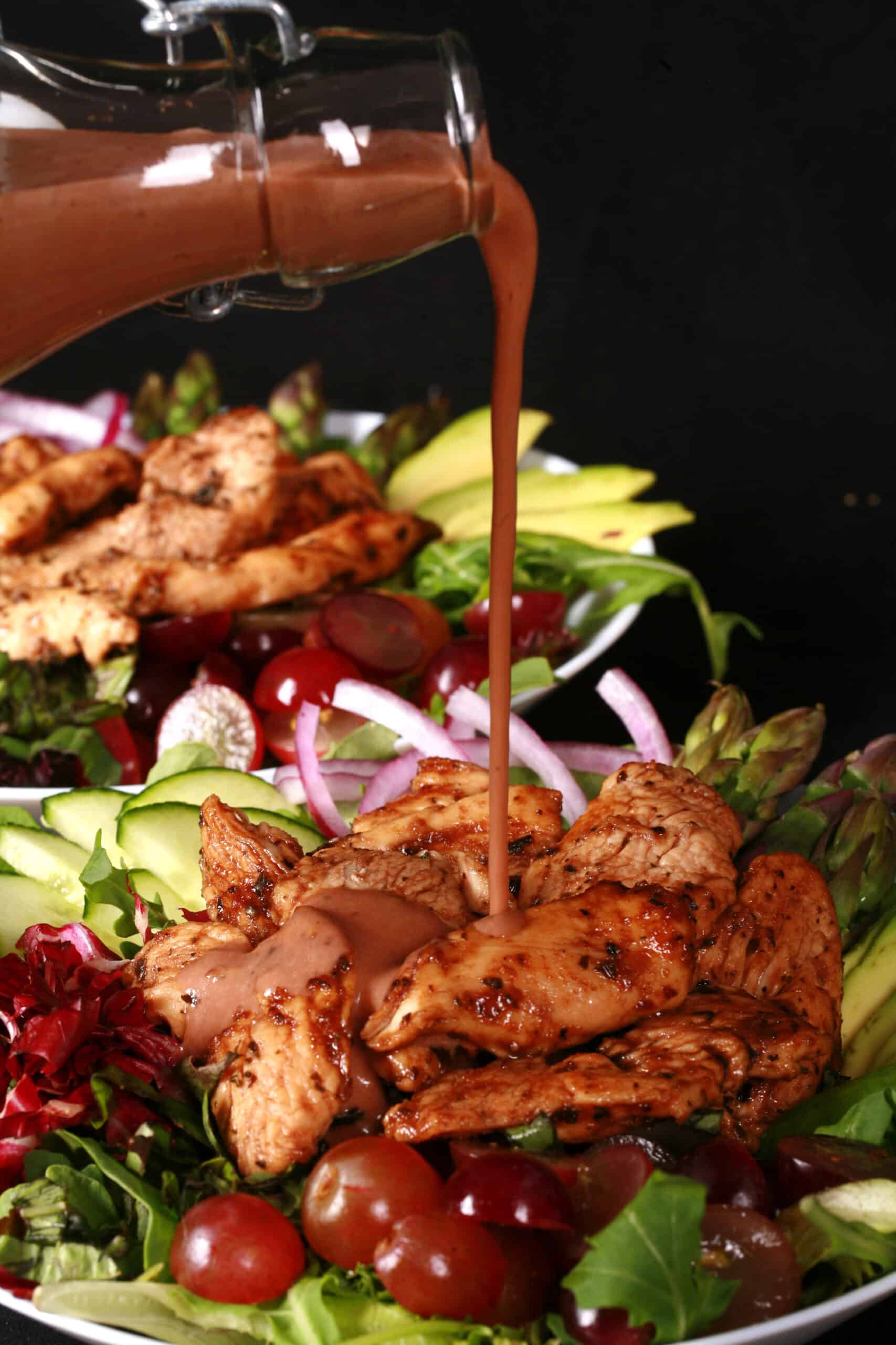 A balsamic chicken with red grapes and a bottle of homemade grape balsamic vinaigrette.