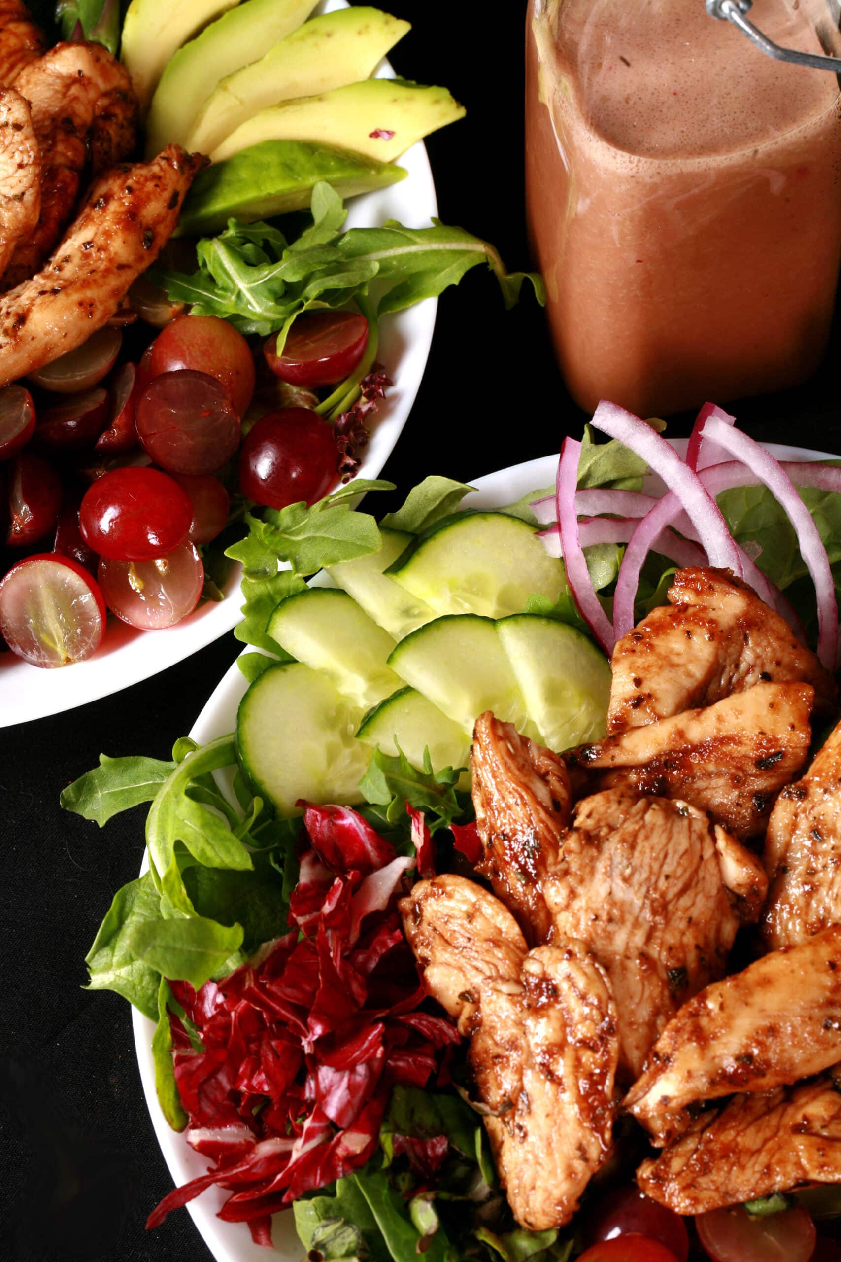 A balsamic chicken with red grapes and a bottle of homemade grape balsamic vinaigrette.