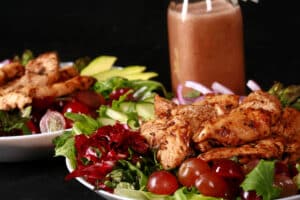 A balsamic chicken with red grapes and a bottle of homemade grape balsamic vinaigrette.