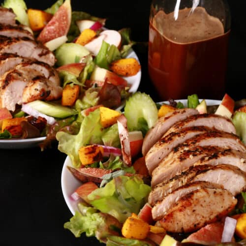 A harvest chicken salad with apples, roasted squash, figs, and more. There is a bottle of maple balsamic vinaigrette.