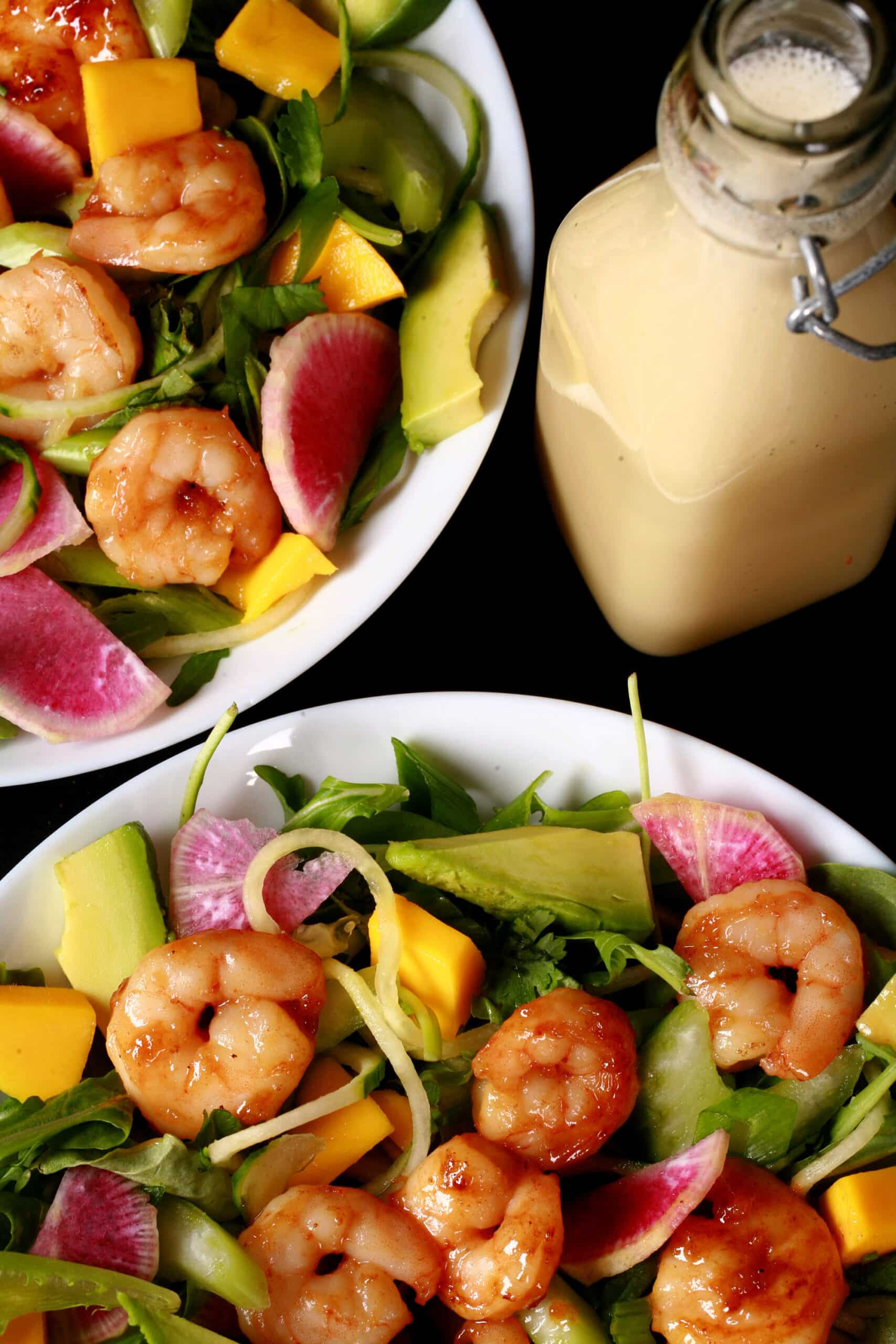 2 bowls of colourful calamansi glazed shrimp salad, with mangoes and a bottle of calamansi vinaigrette.