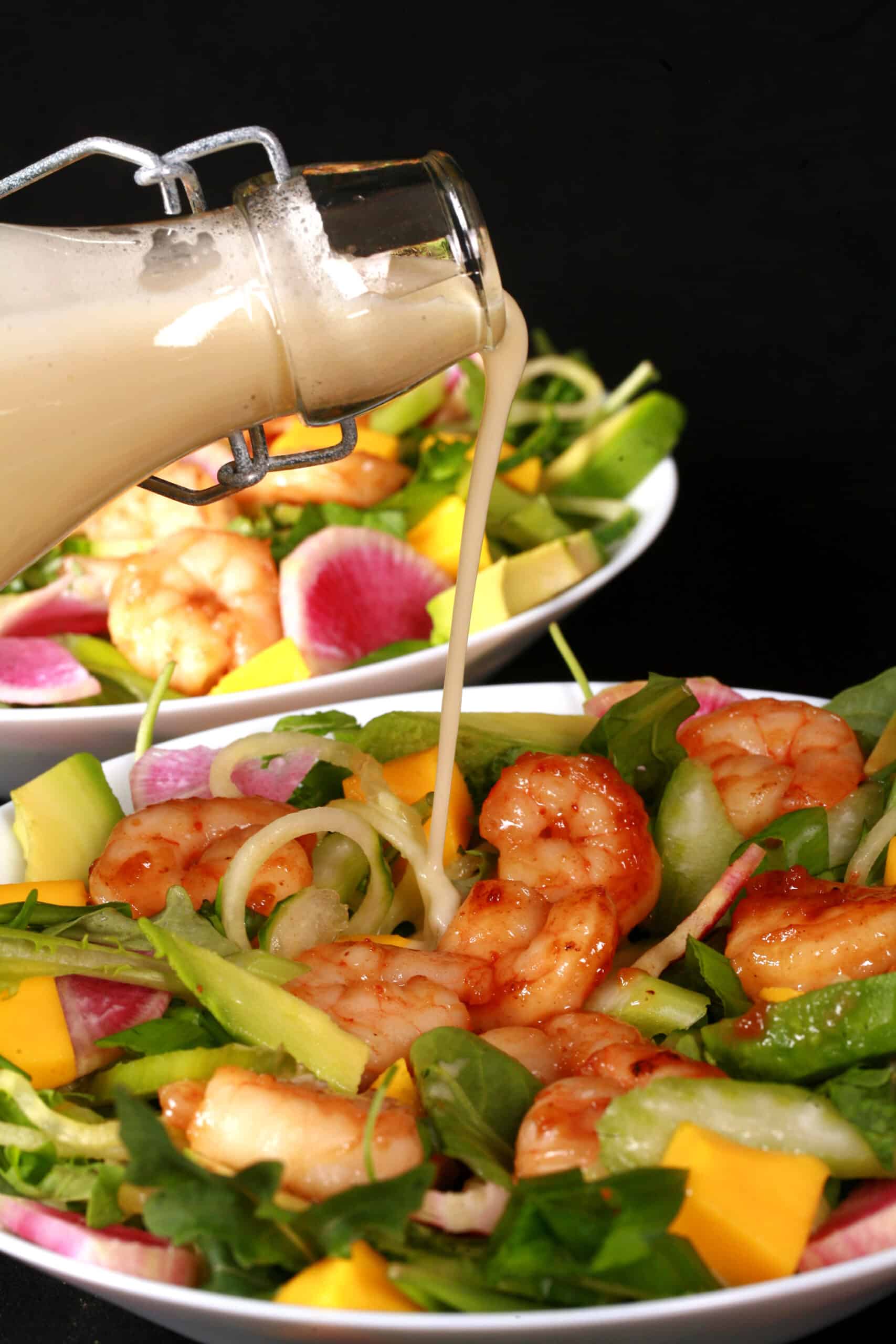 2 bowls of colourful mango shrimp salad, with a bottle of calamansi vinaigrette.