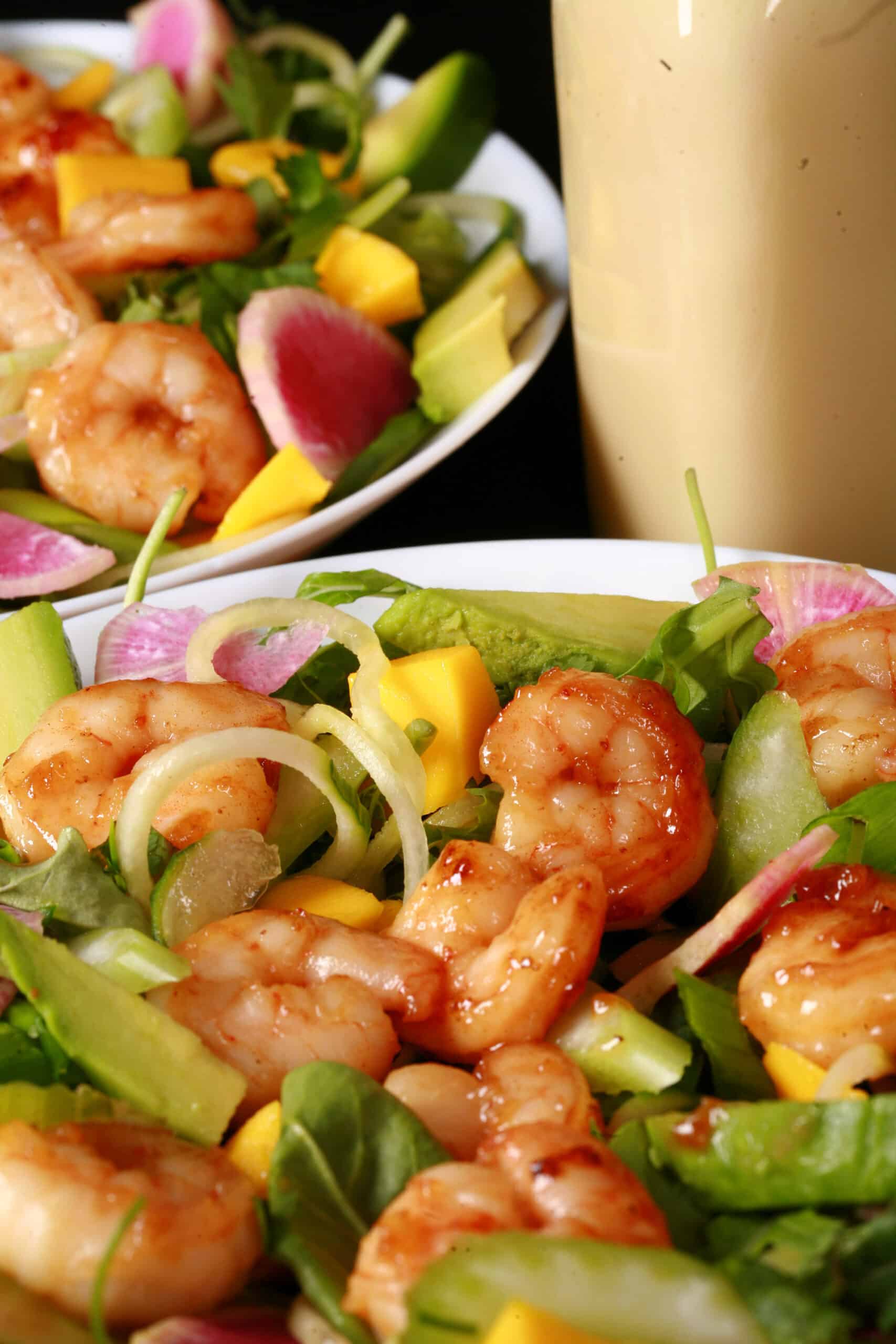 2 bowls of colourful mango shrimp salad, with a bottle of calamansi vinaigrette.