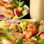 2 bowls of colourful mango shrimp salad, with a bottle of calamansi vinaigrette.