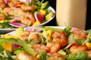 2 bowls of colourful mango shrimp salad, with a bottle of calamansi vinaigrette.