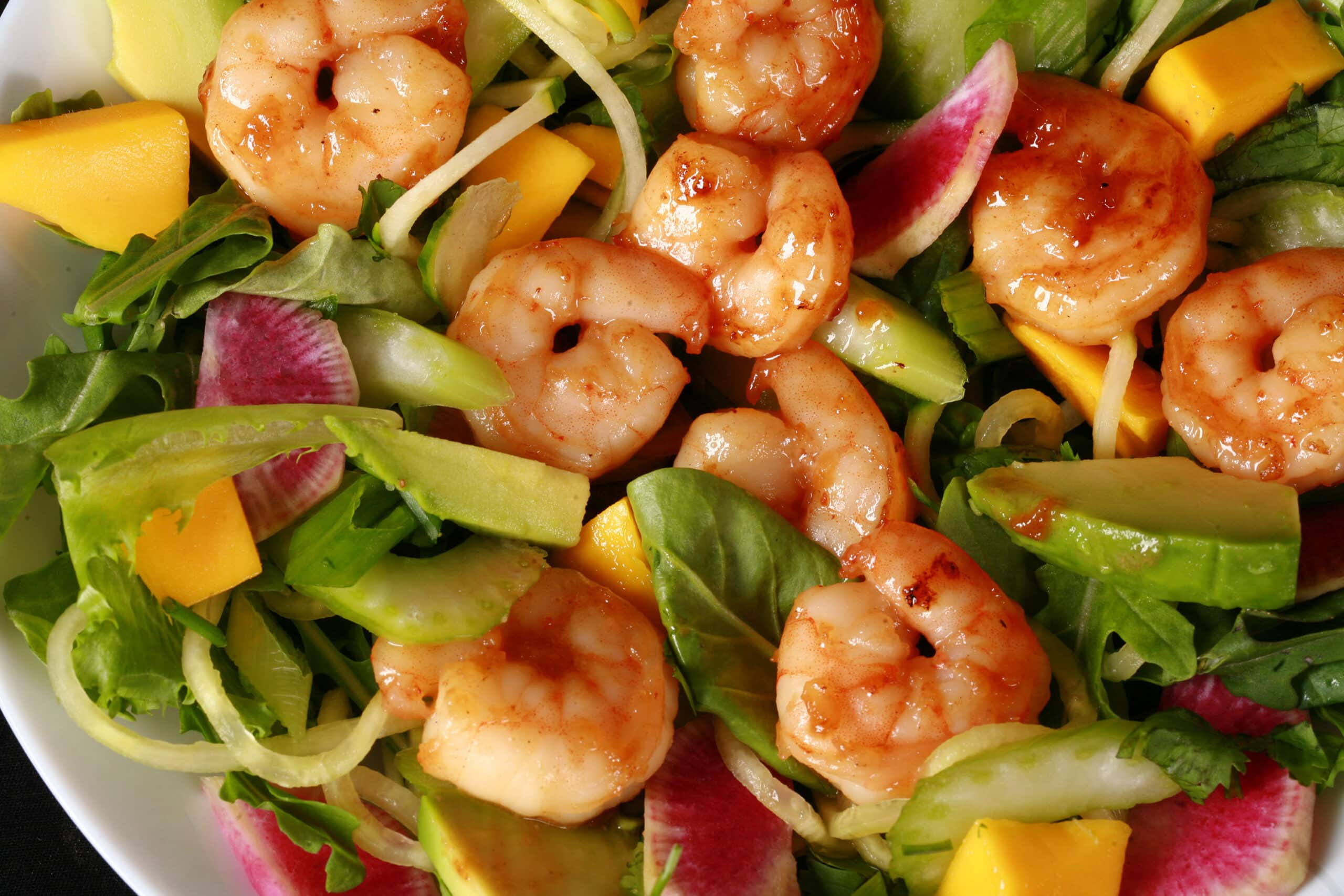 2 bowls of colourful calamansi glazed shrimp salad, with mangoes and a bottle of calamansi vinaigrette.