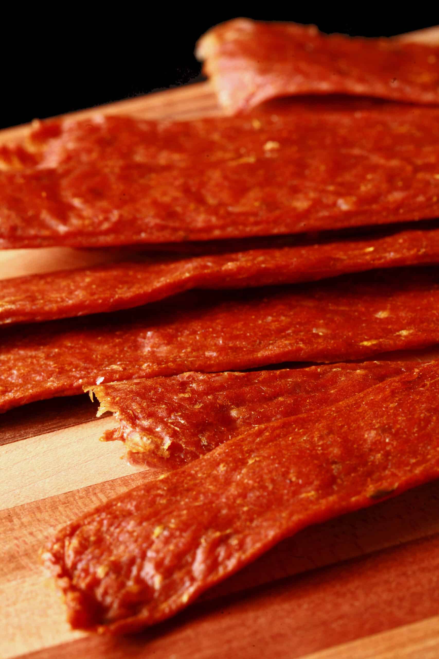 Several strips of shawarma chicken jerky on a cutting board.