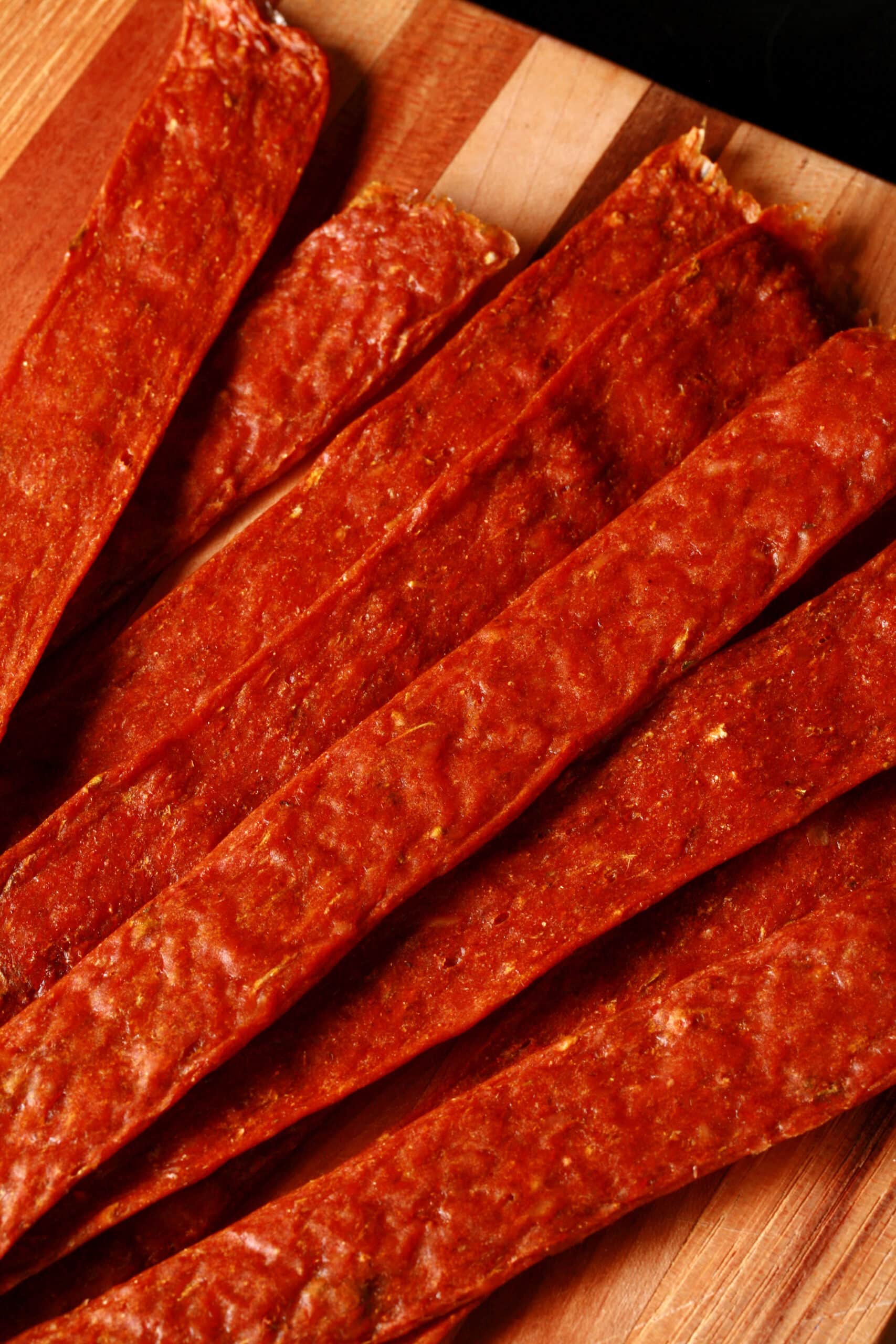 Several strips of shawarma spiced chicken jerky on a cutting board.