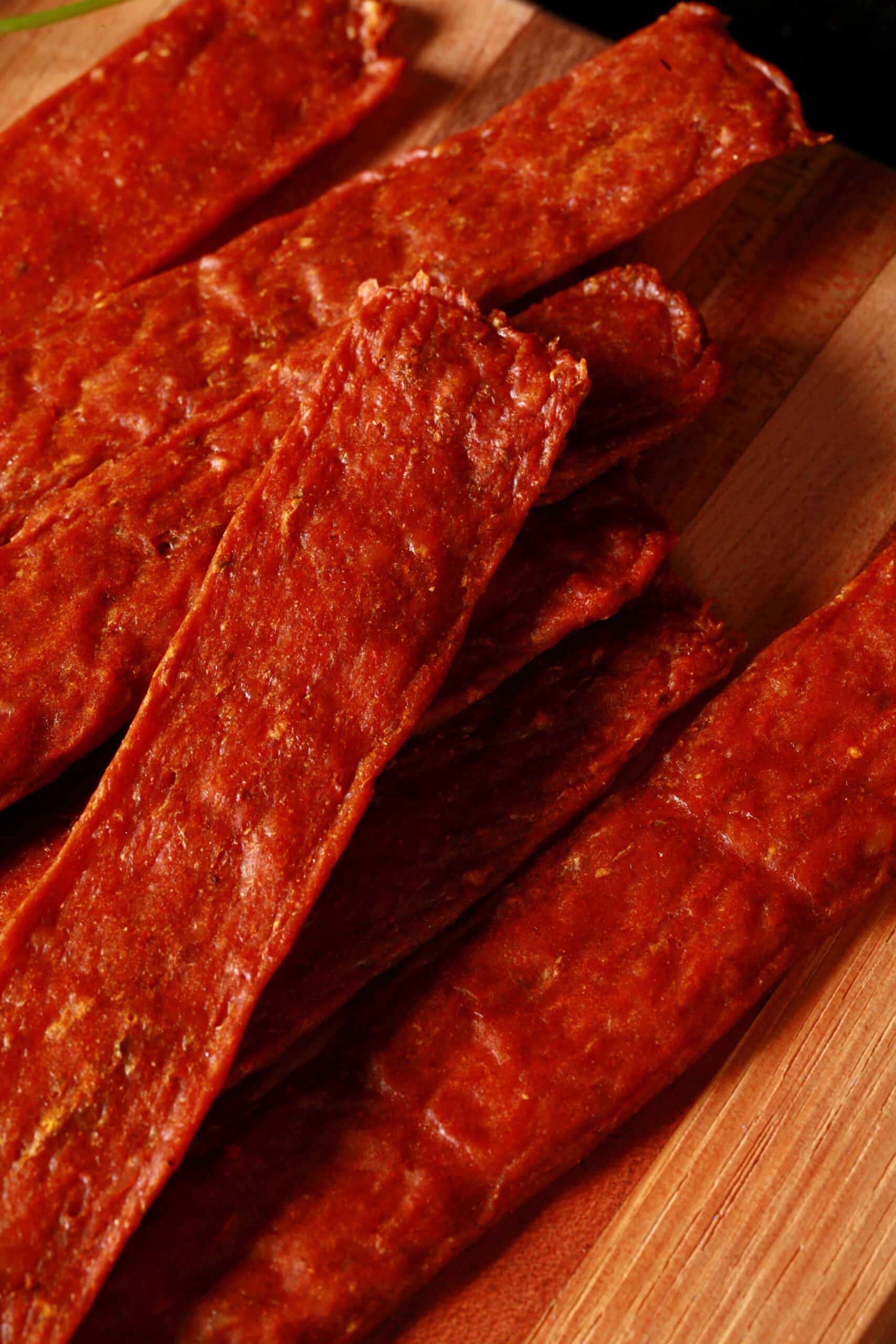 Several strips of shawarma spiced chicken jerky on a cutting board.