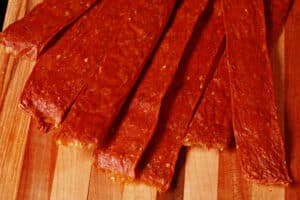 Several strips of shawarma spiced chicken jerky on a cutting board.