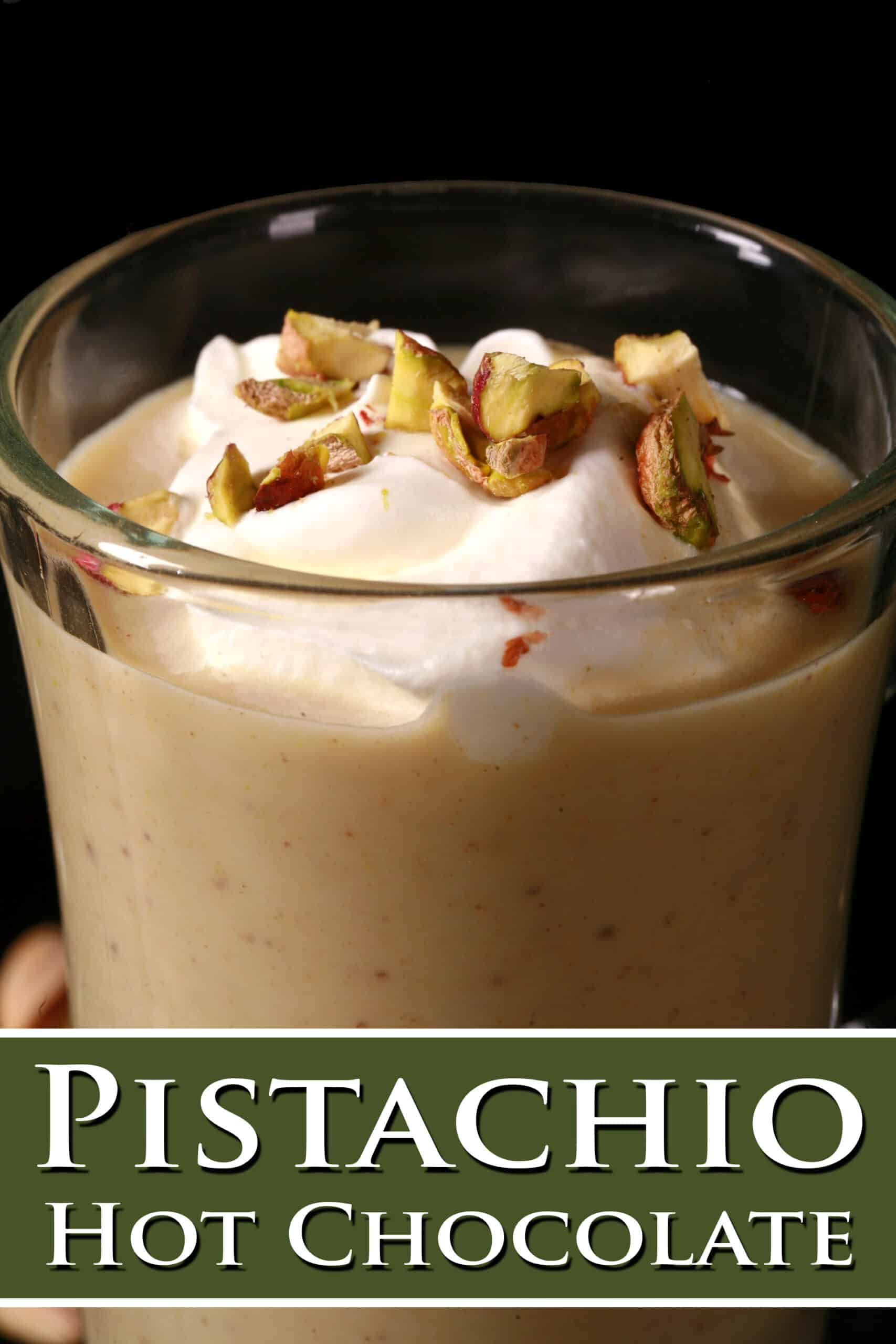 A glass mug of pistachio white hot chocolate, topped with whipped cream and chopped pistachios. Overlaid text says pistachio hot chocolate.