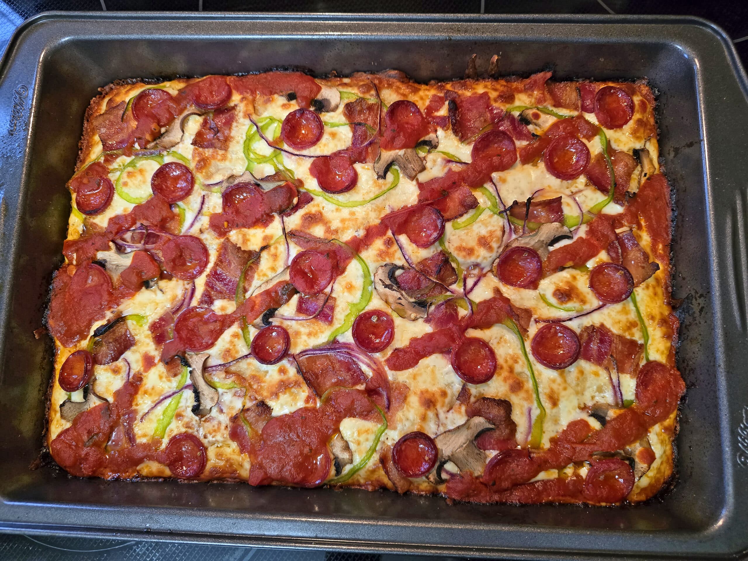 A freshly baked detroit style gluten free pizza in a pan.