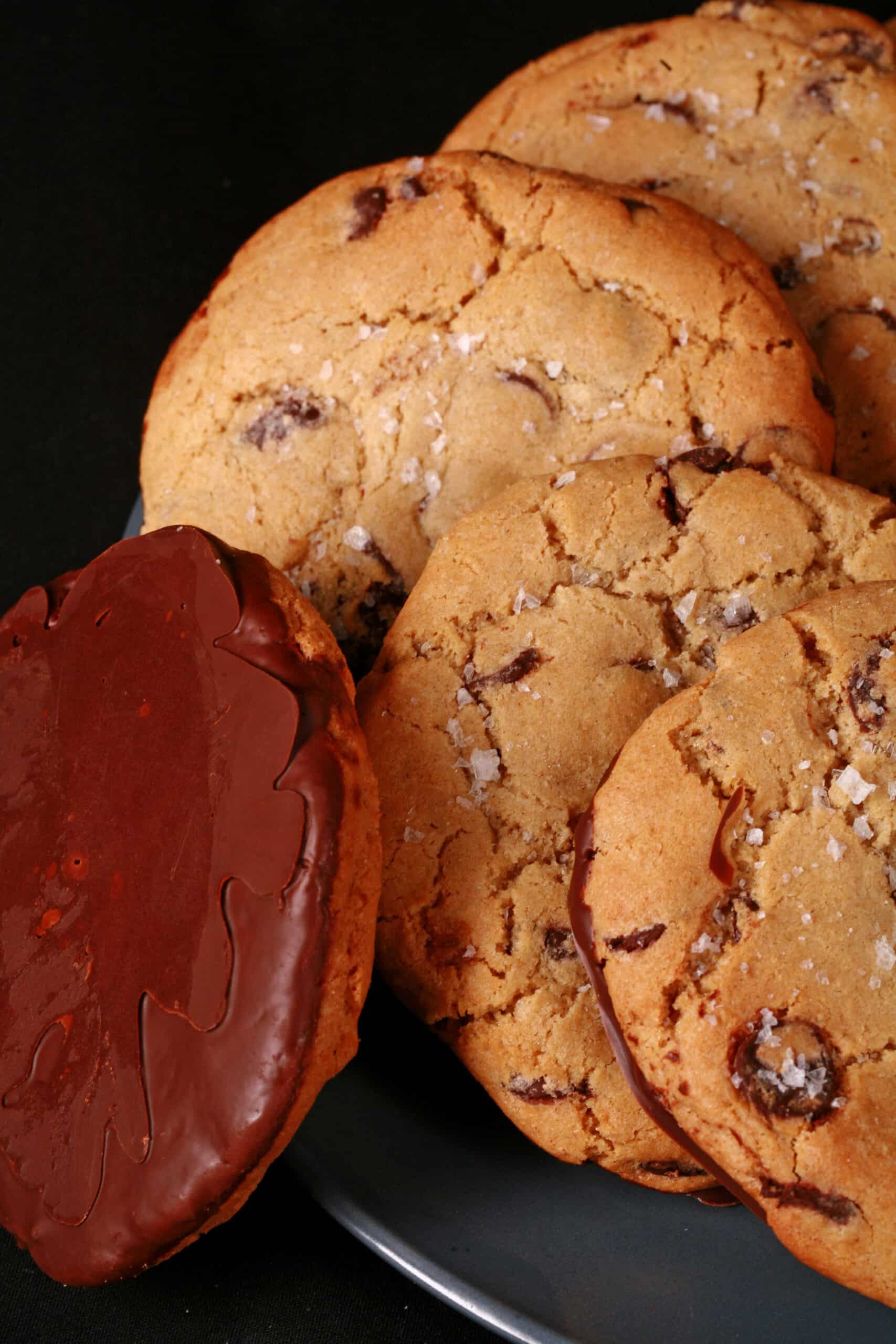 A plate of huge chocolate dipped gluten free jacques torres chocolate chip cookies sprinkled with sea salt.