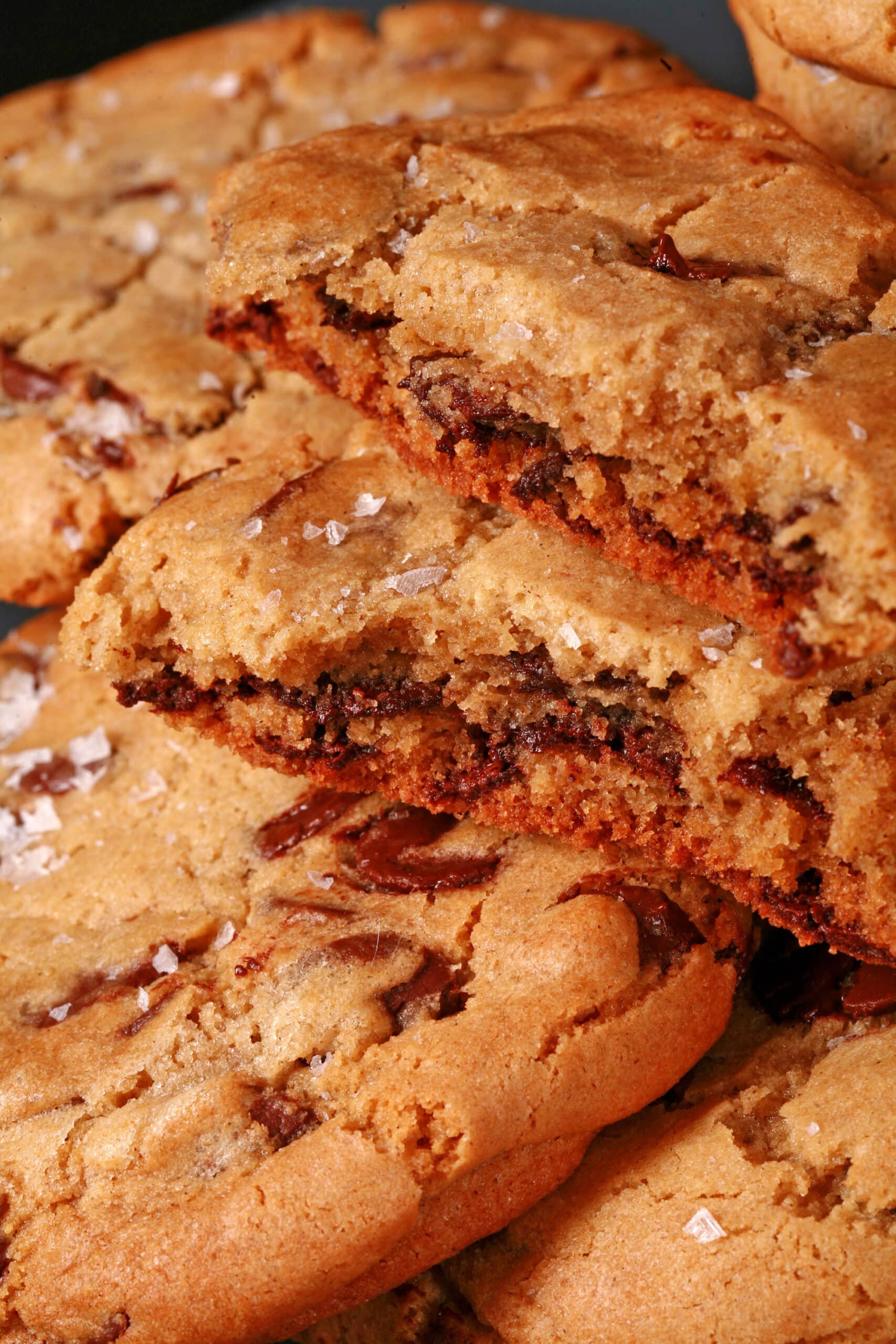 A plate of huge chocolate dipped gluten free jacques torres chocolate chip cookies sprinkled with sea salt.