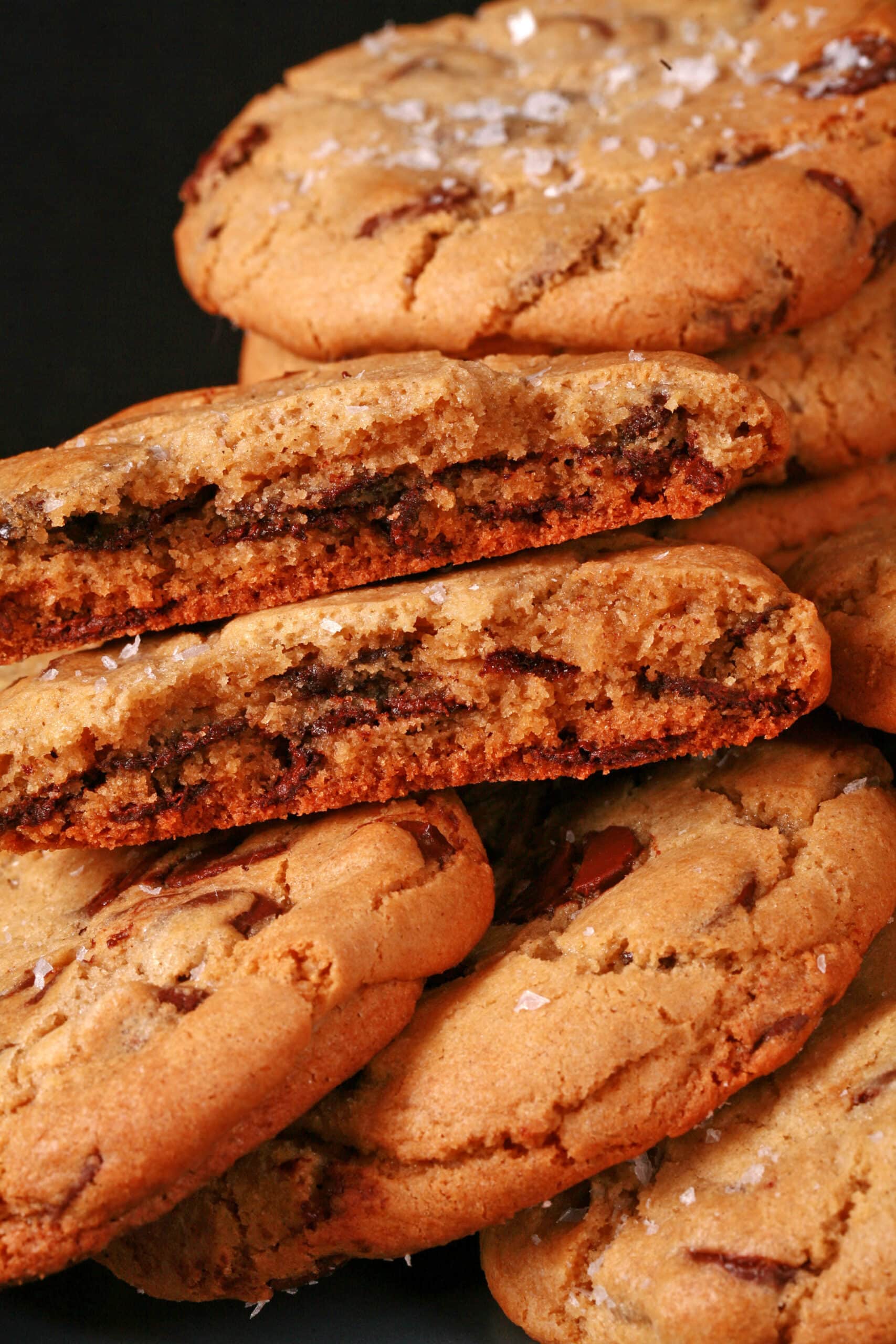 A plate of huge chocolate dipped gluten free jacques torres chocolate chip cookies sprinkled with sea salt.