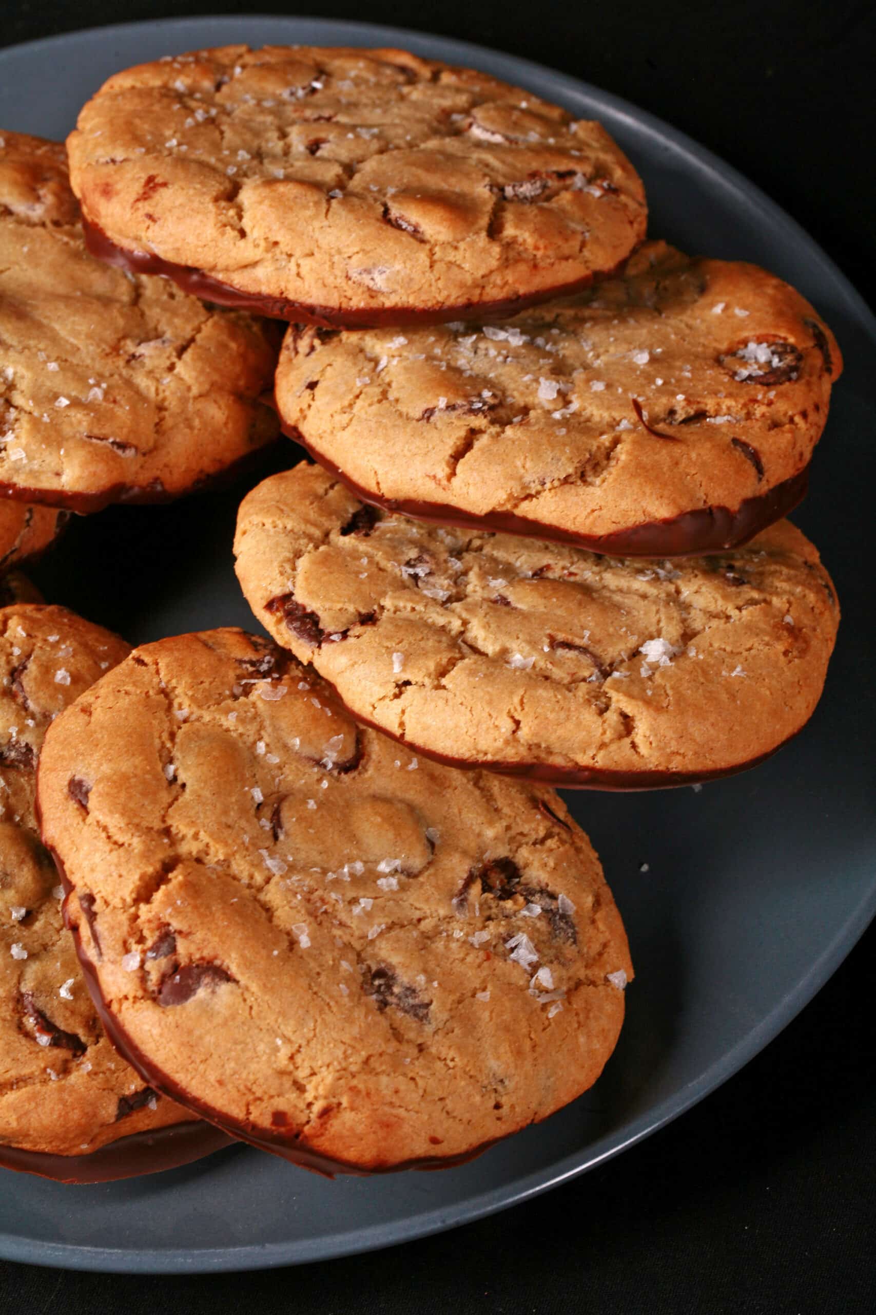 A plate of huge gluten free chocolate chip cookies sprinkled with sea salt.